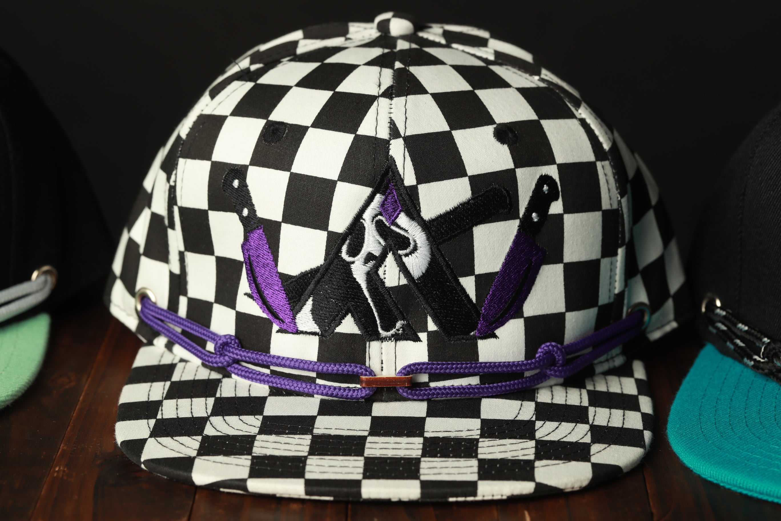 A black and white checkered baseball cap with purple accents, featuring a graphic design on the front.