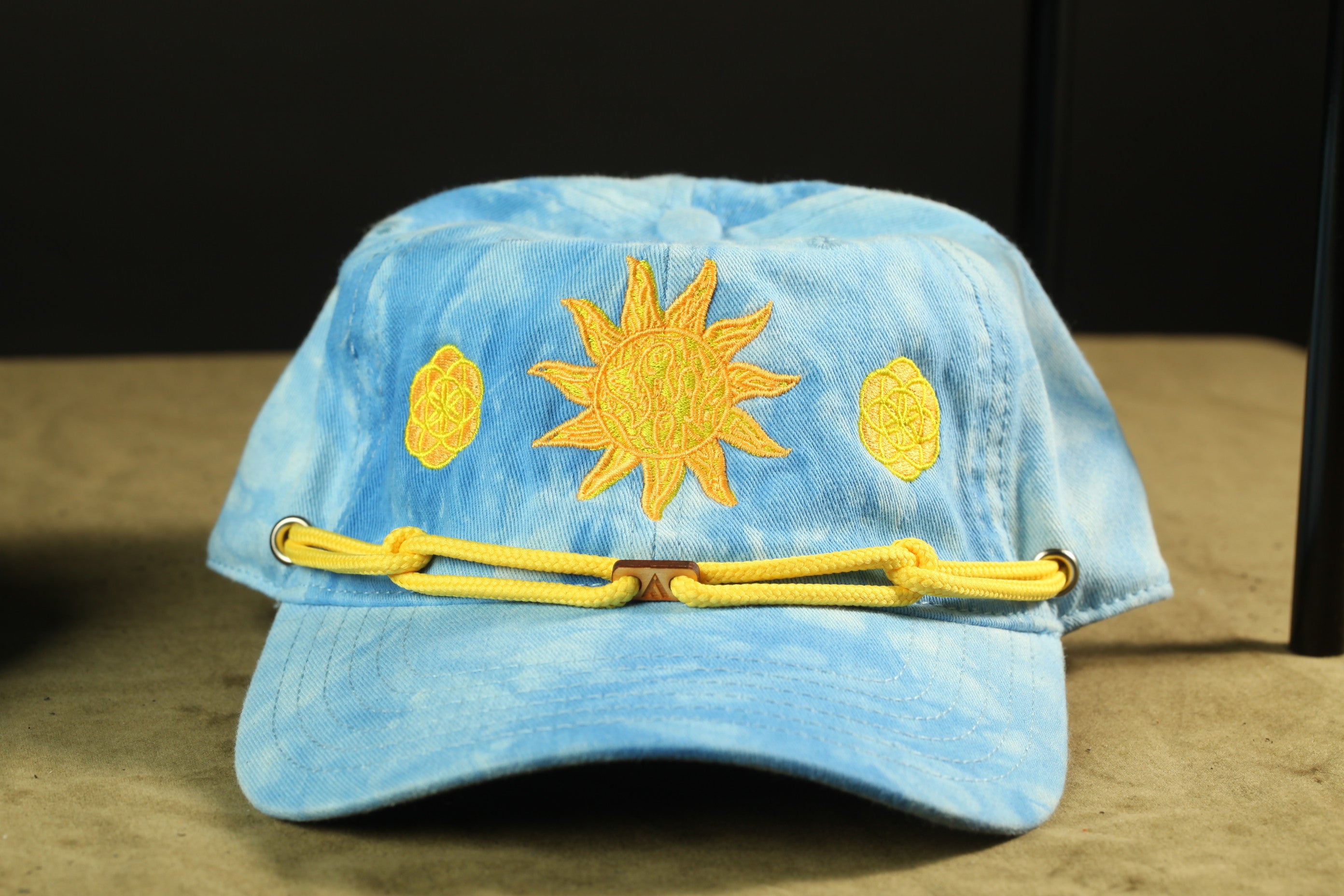 A blue baseball cap with a sun embroidered on it, featuring three yellow sun motifs on the front.