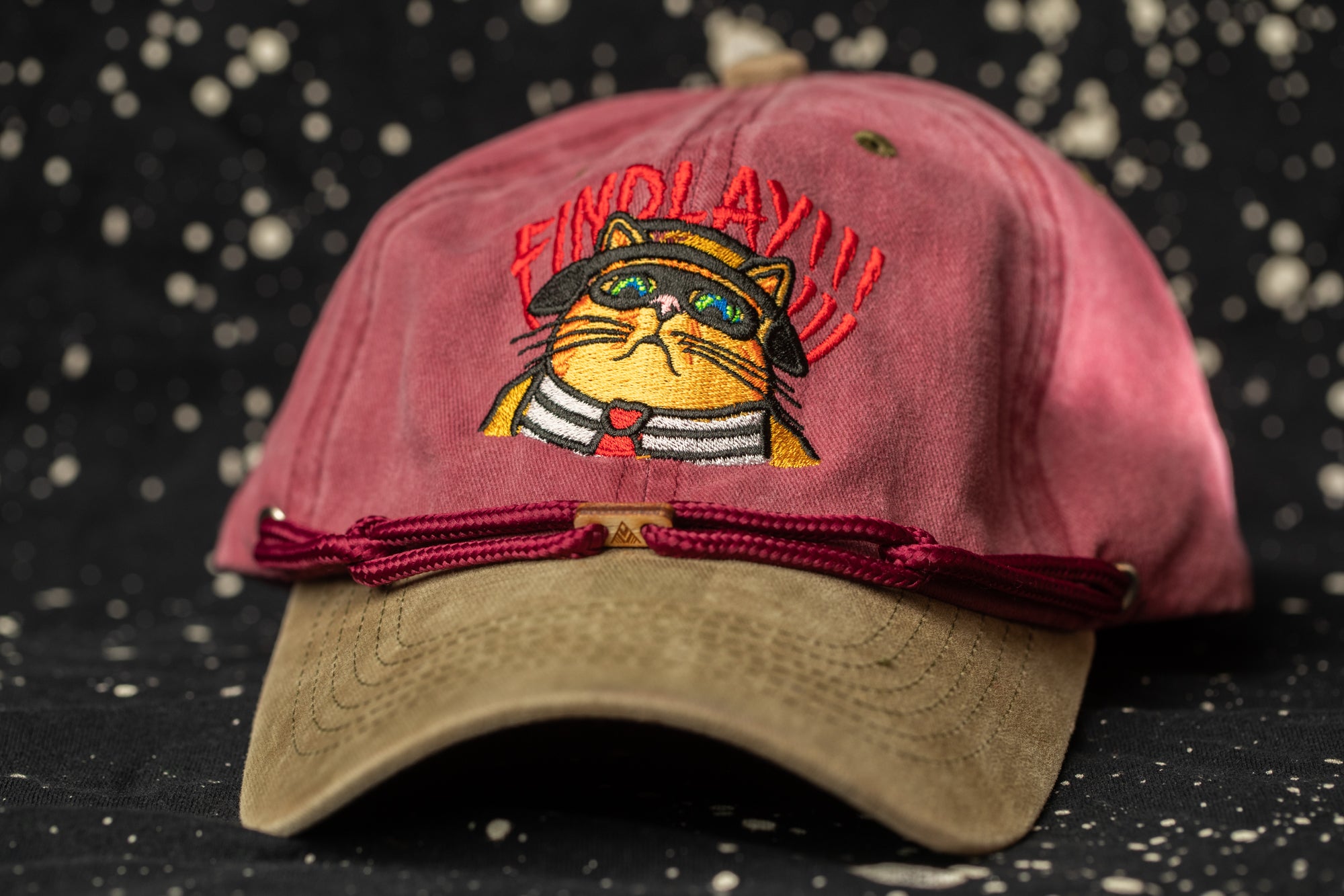 A red baseball cap with a cat embroidered on it, featuring a red band around the brim.