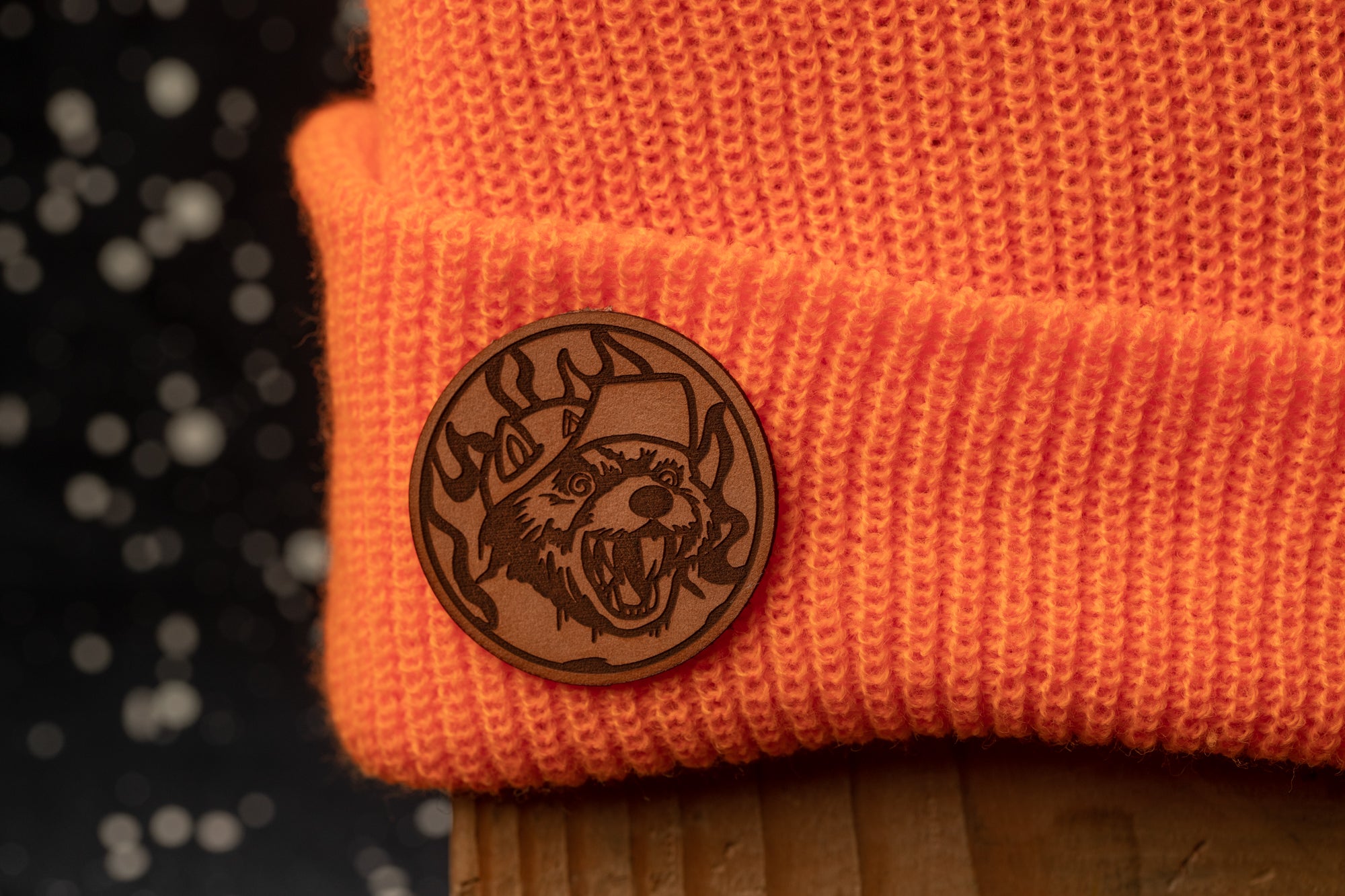 a close-up of an orange knit cap with a circular badge or emblem on it, which appears to be a logo or design.