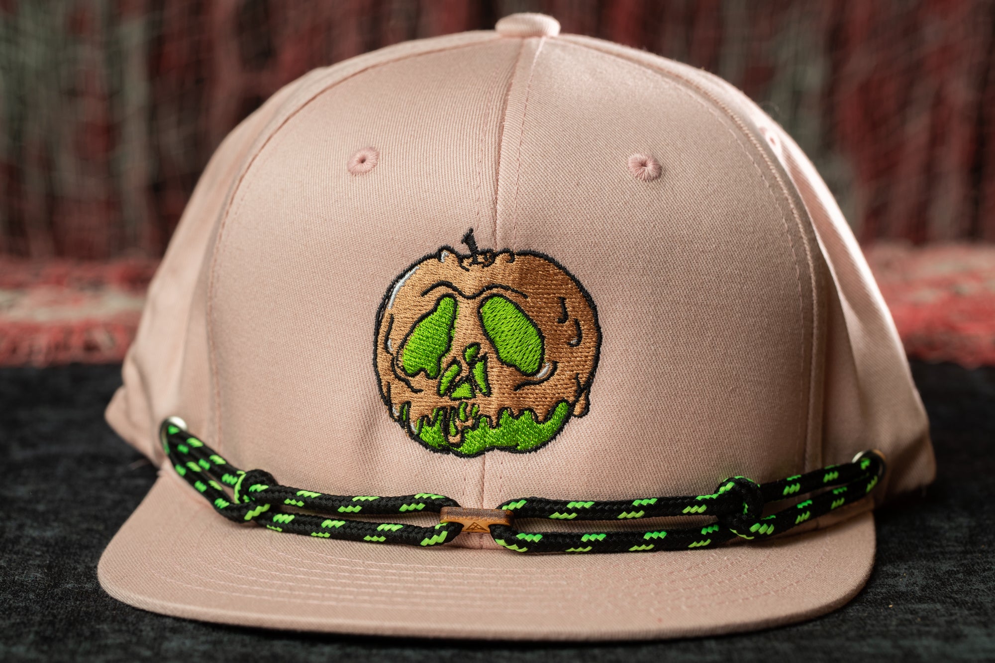 A pink baseball cap with a green skull design on the front.