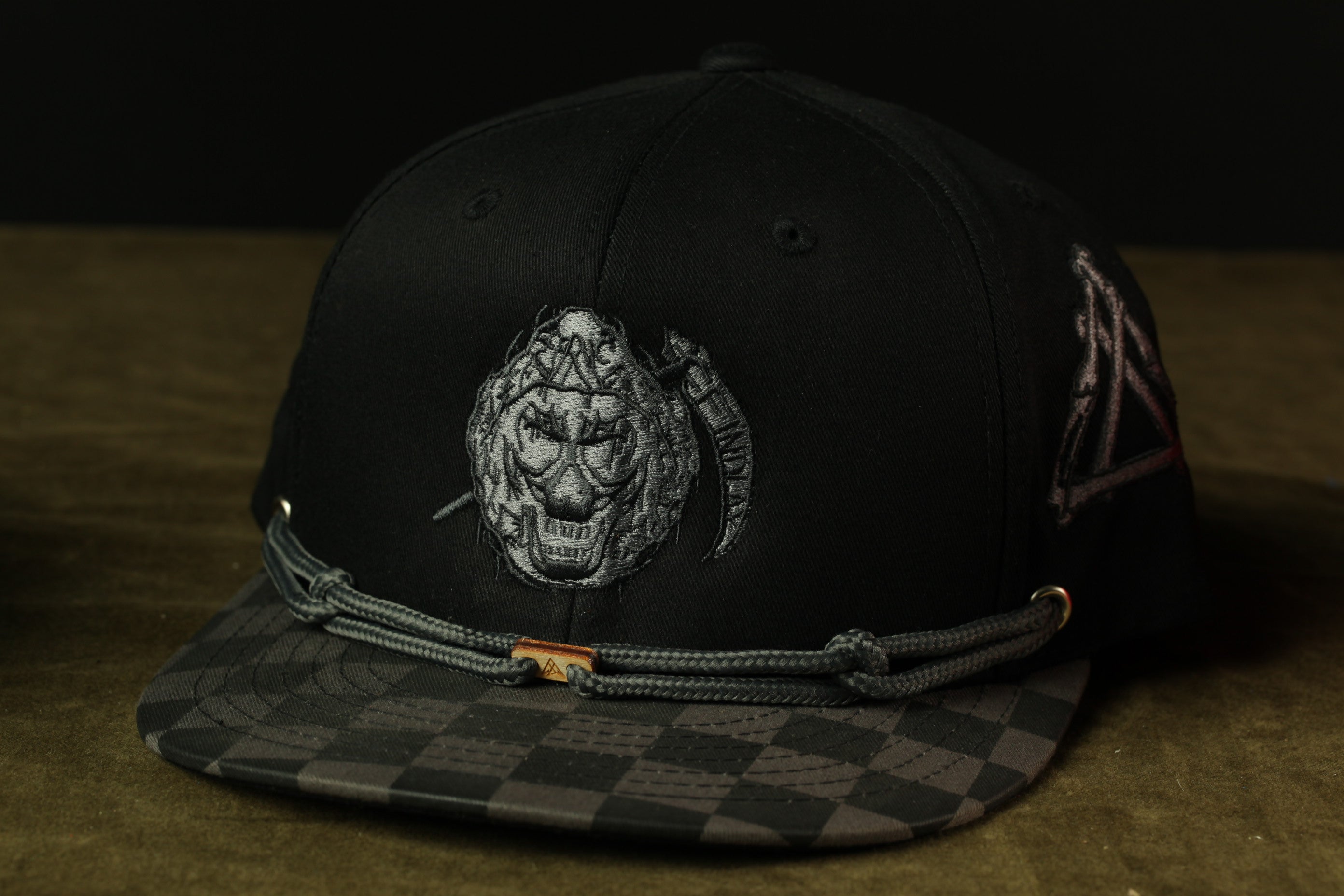 A black baseball cap with a checkered pattern and a skull embroidered on the front.