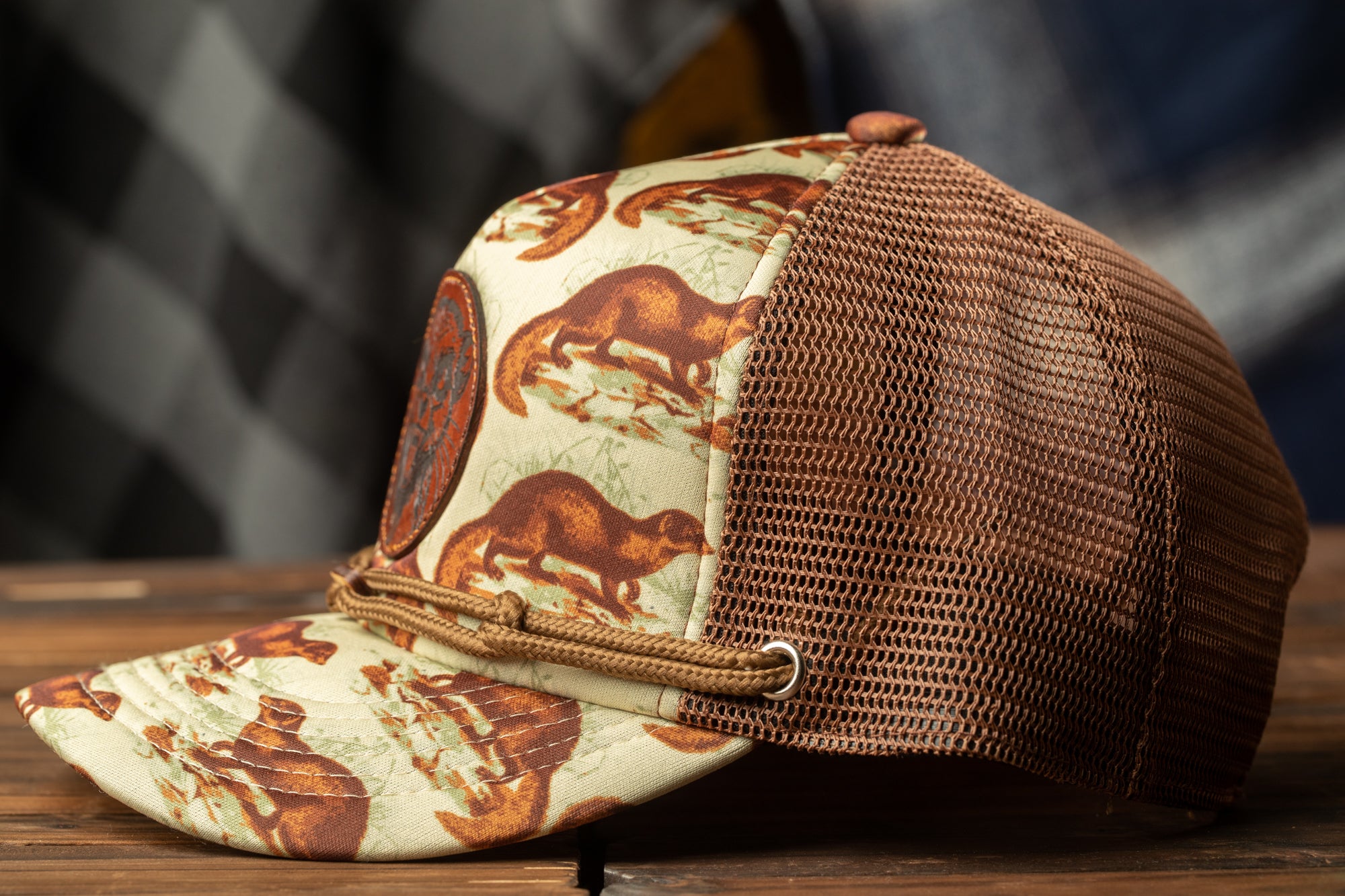 A brown and white baseball cap with a mesh panel and a circular logo featuring a brown animal on the front.
