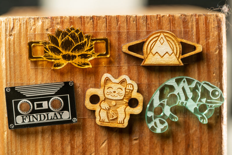 a wooden surface with various objects attached to it, including a gold flower, a wooden cat, a green chameleon, and a black and white tape recorder.