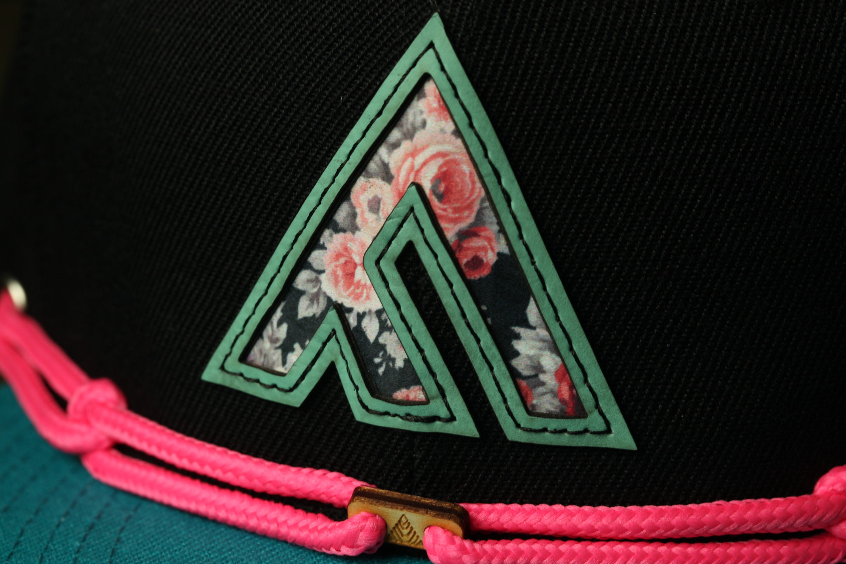 A close-up view of a black baseball cap with a floral pattern on the front.