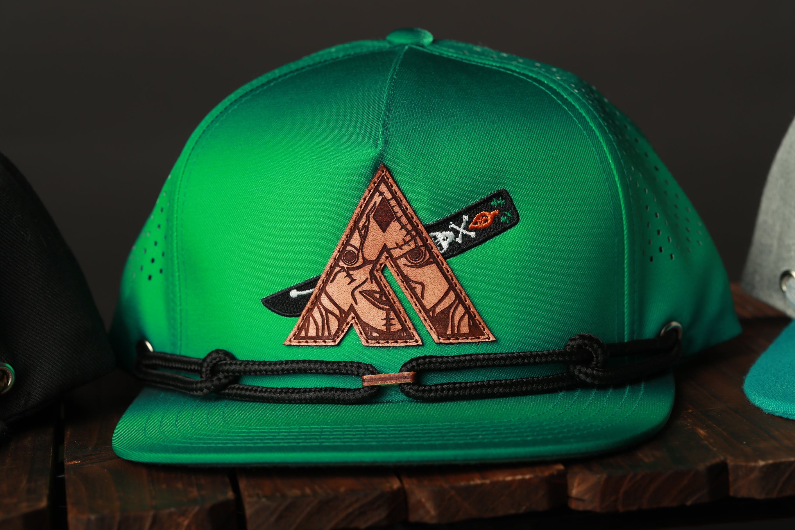 A green baseball cap with a unique embroidered logo on the front.