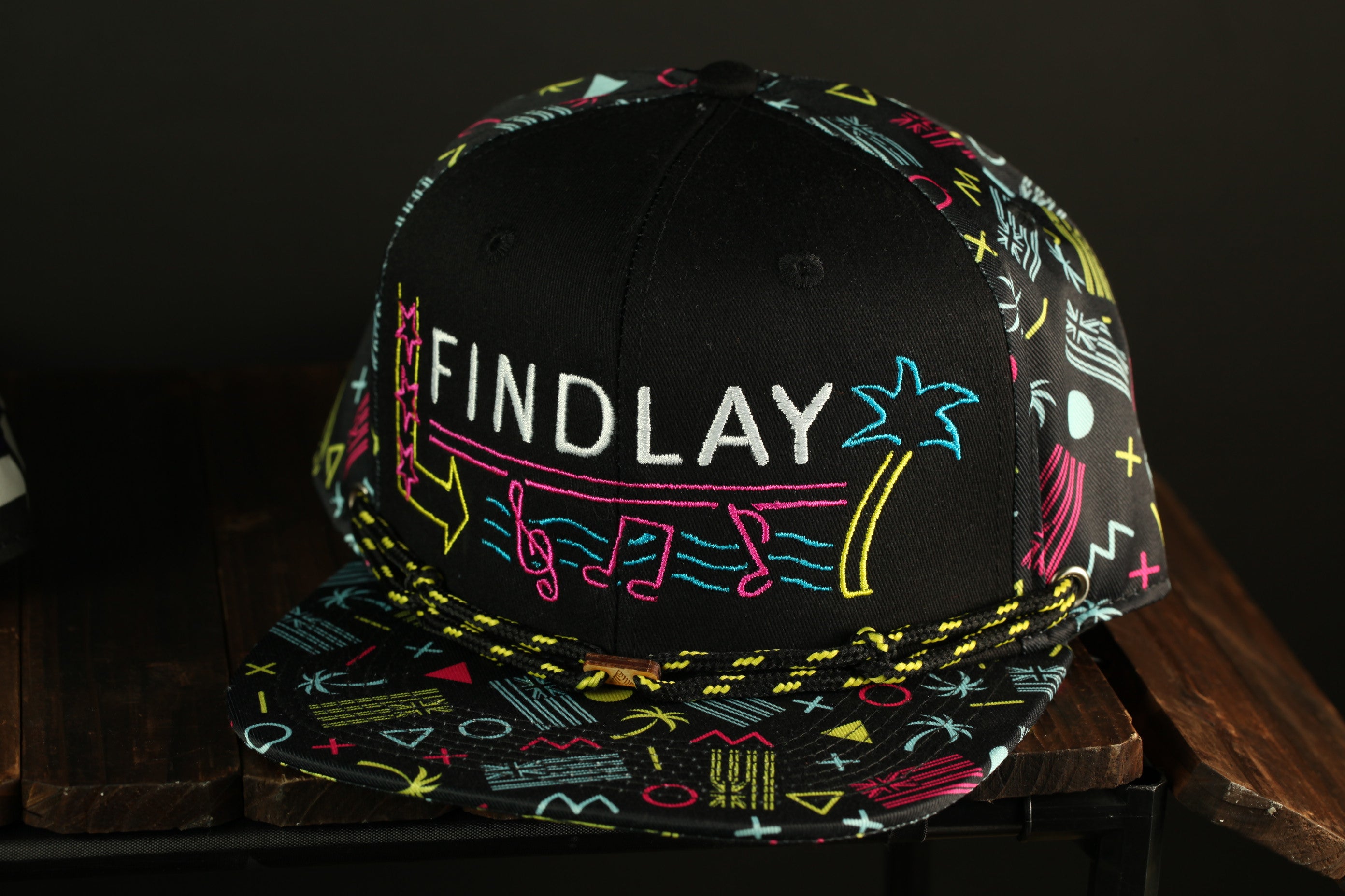 A black baseball cap with colorful patterns and text, including the word "FINDlay" on the front.