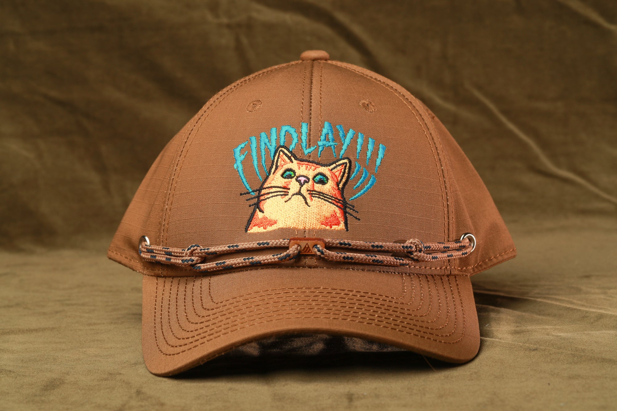 A brown baseball cap with a cat embroidered on it, featuring the text "FIND LAYY!"