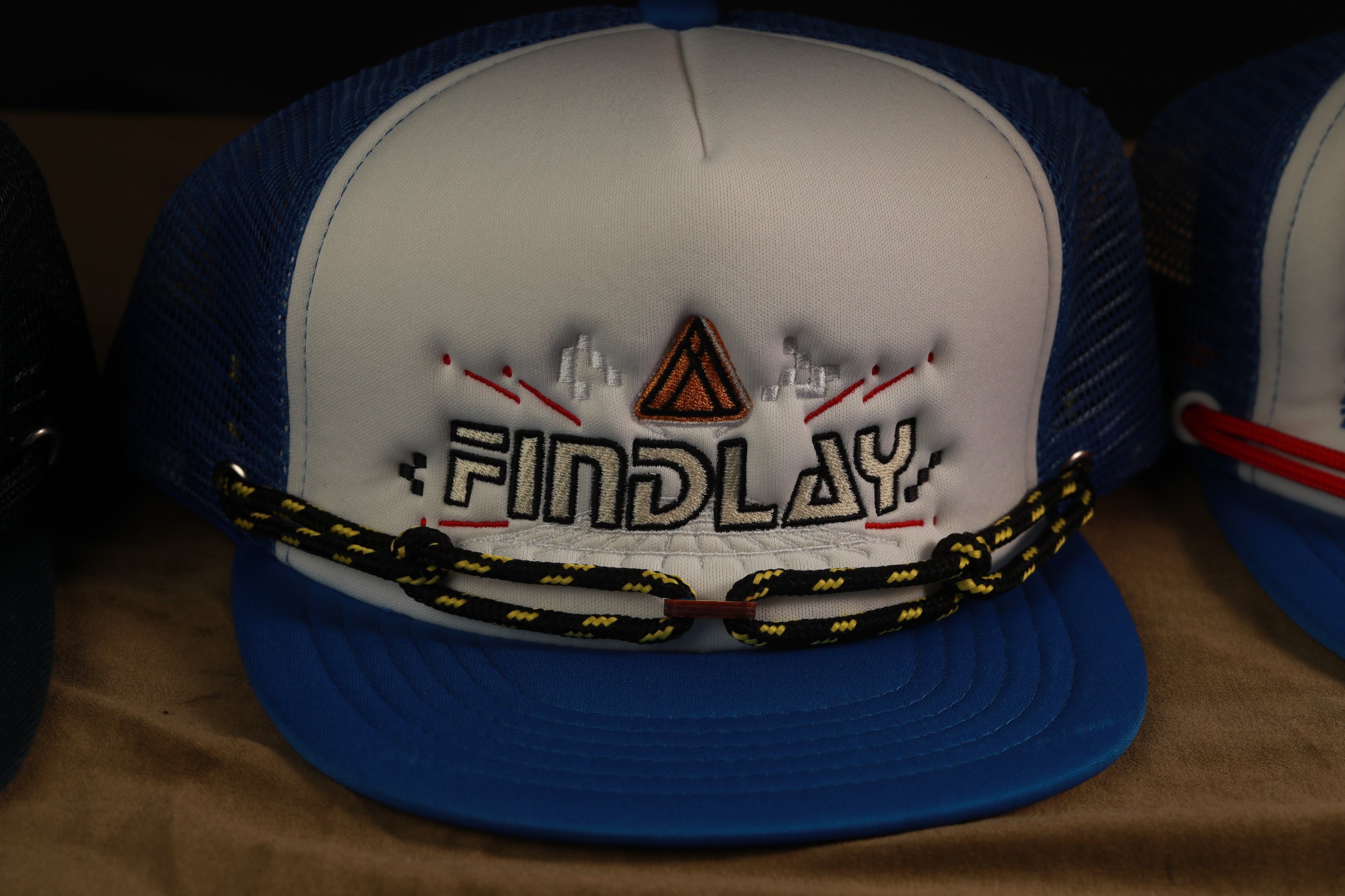 A blue and white baseball cap with the word "FINDlay" embroidered on it.