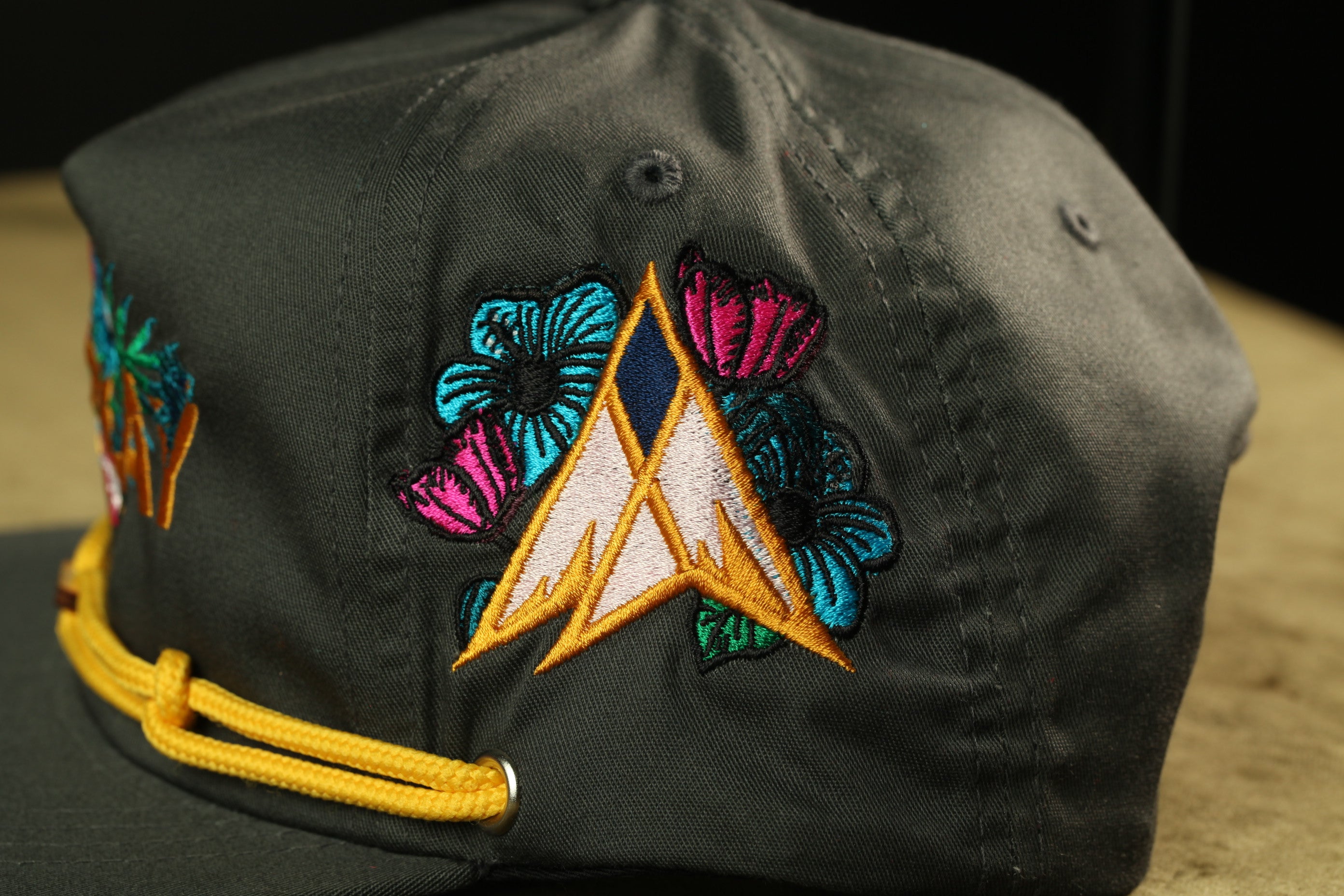 A close-up view of a black baseball cap with colorful floral embroidery on the front.