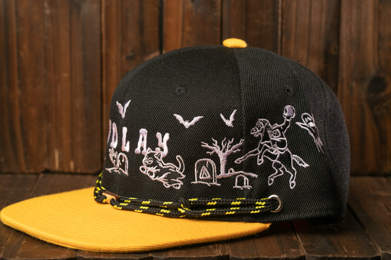 A black baseball cap with a yellow brim, featuring embroidered designs and text.
