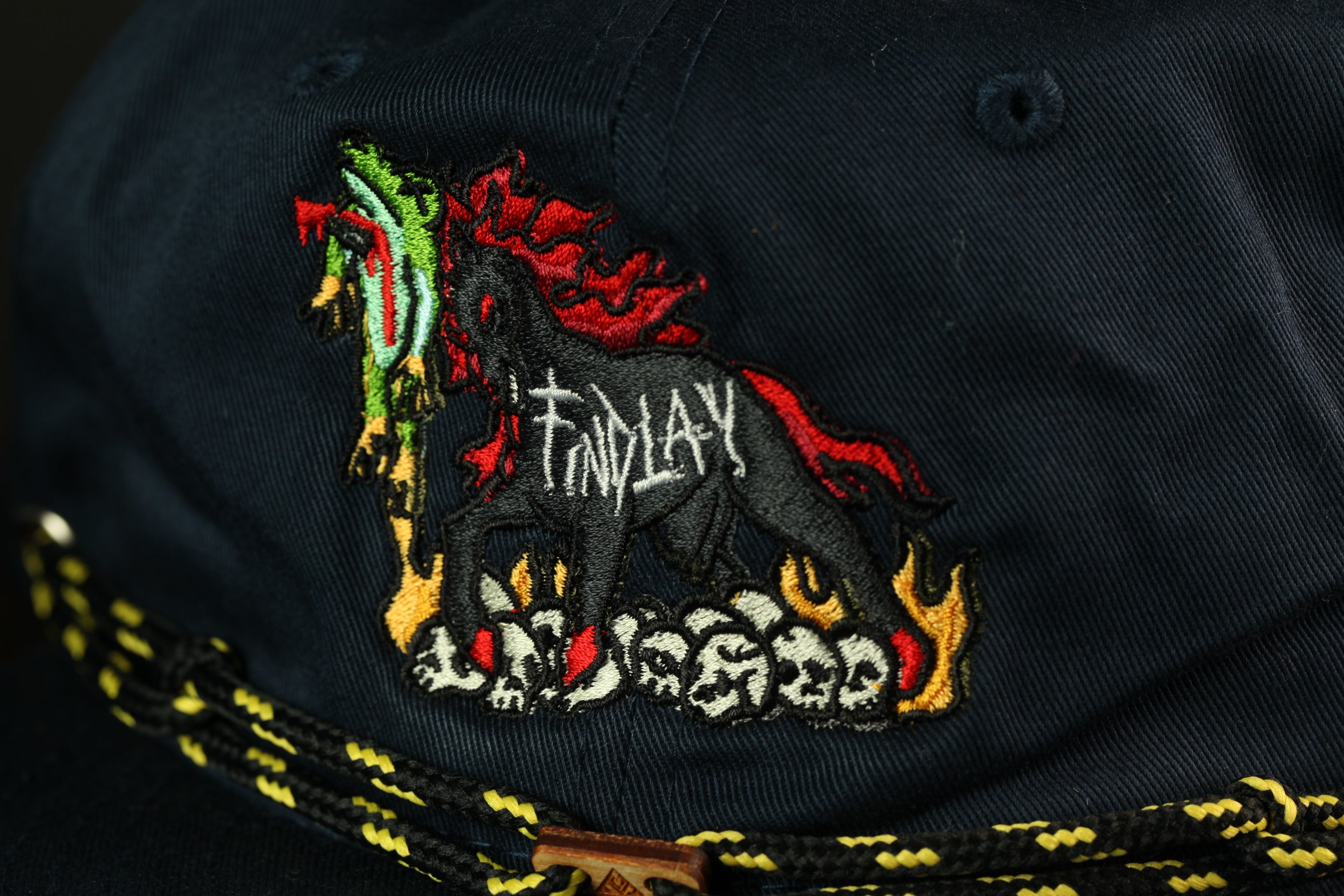 a close-up view of a dark blue baseball cap with a colorful embroidered design on the front.