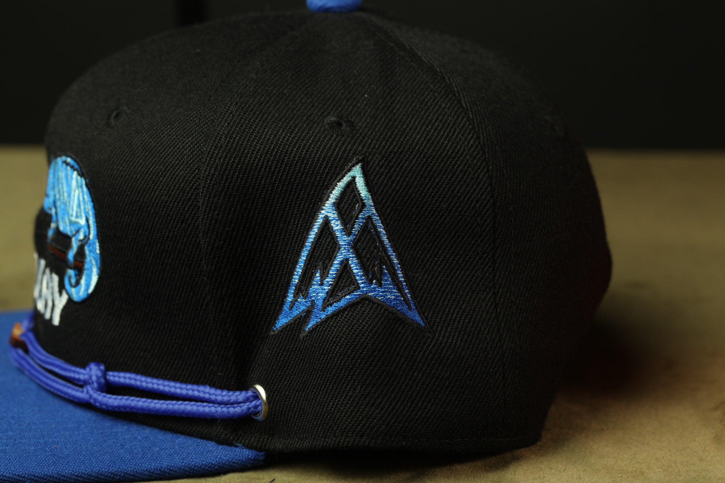 A black baseball cap with a blue logo on the front.