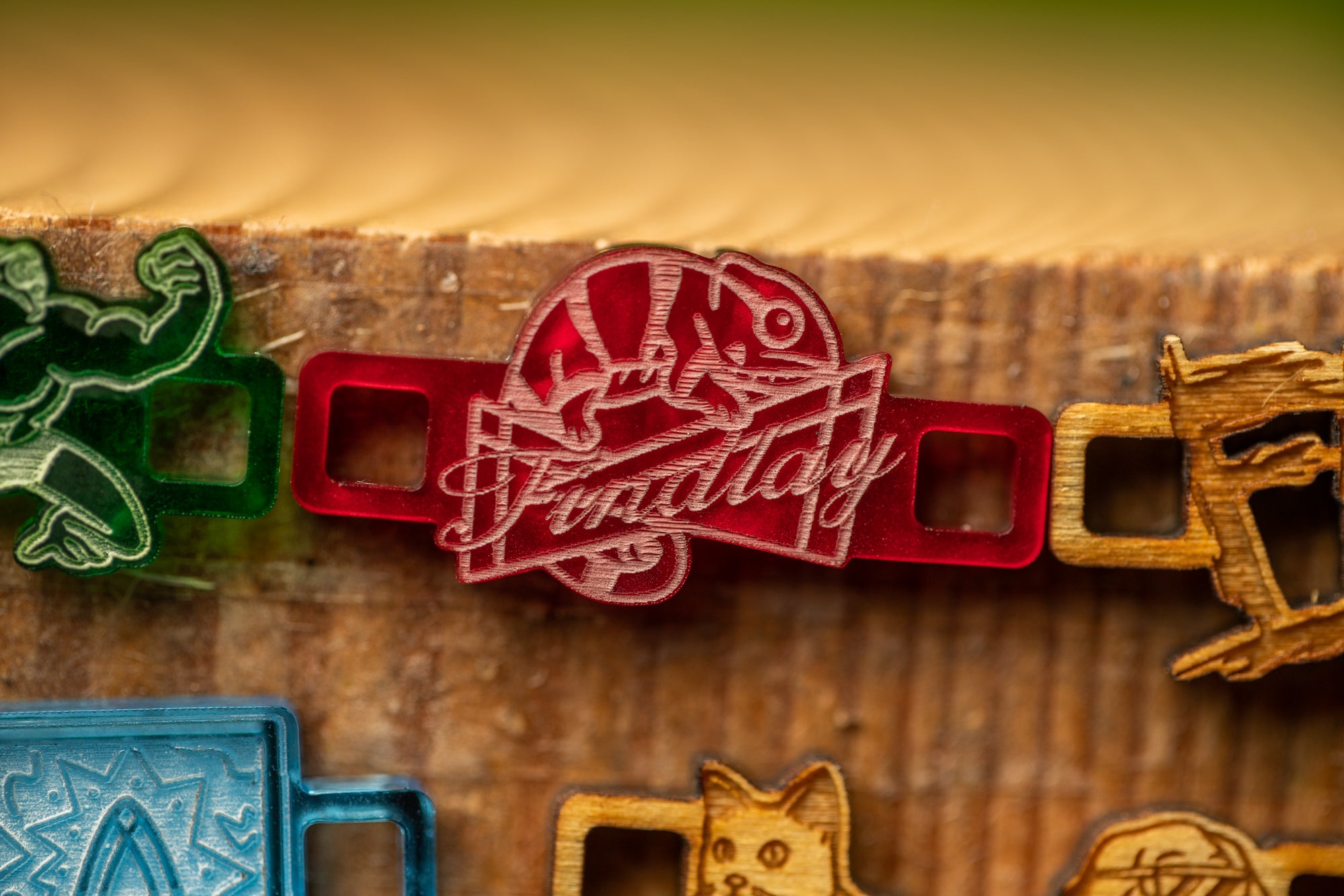 a red plastic charm with a chameleon design, attached to a wooden surface.
