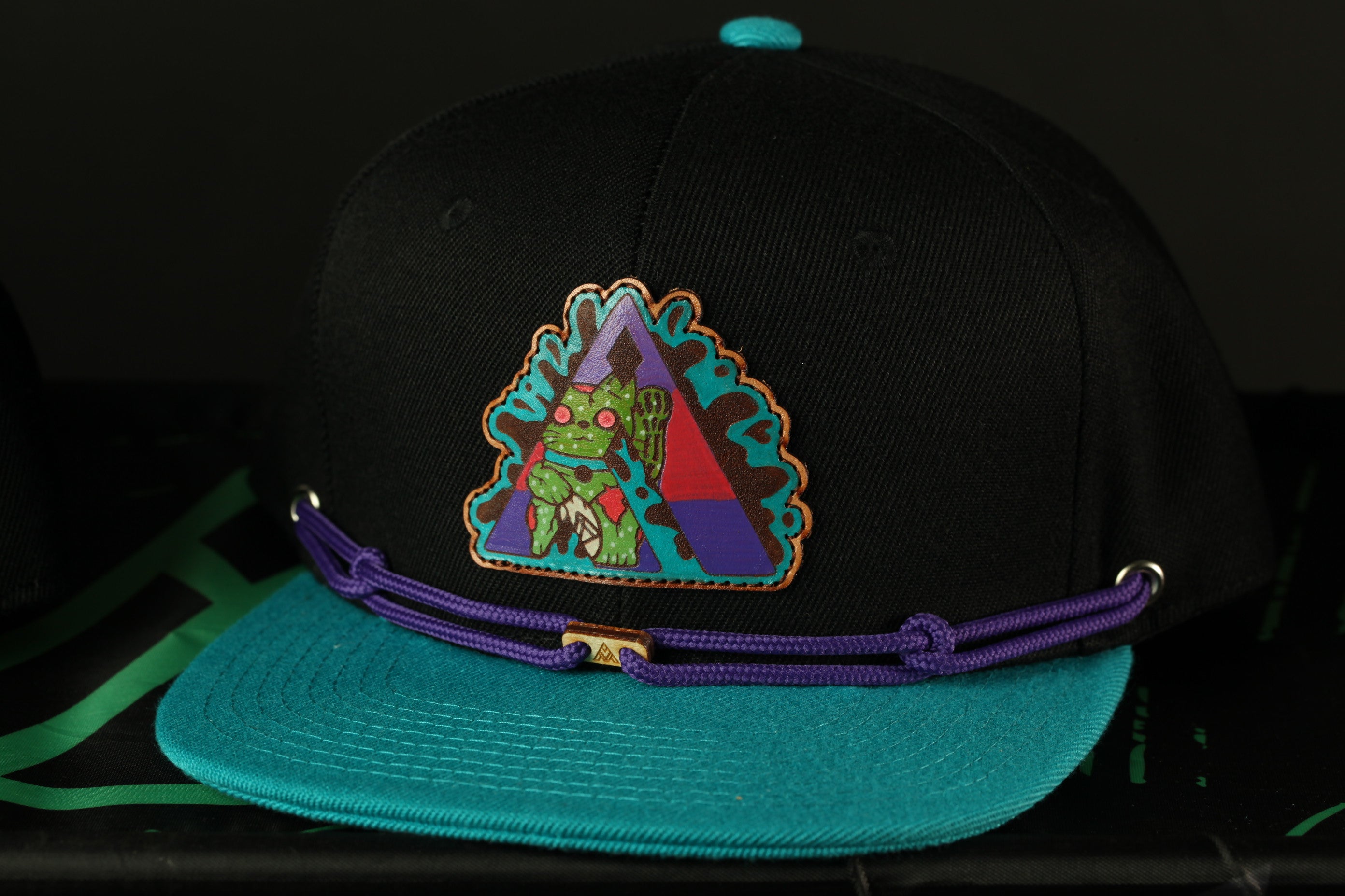 A black baseball cap with a colorful, cartoonish design on the front.