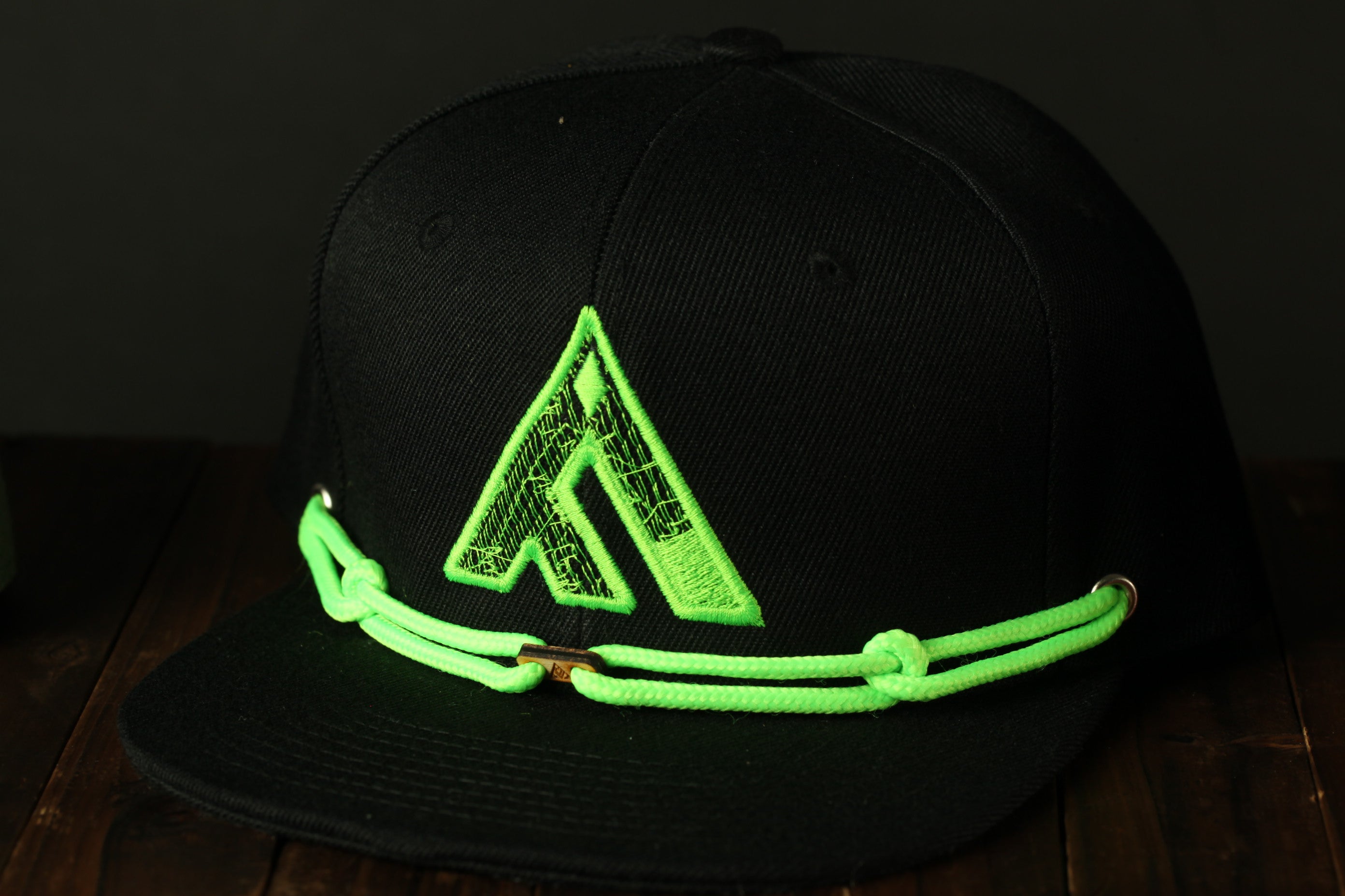 A black baseball cap with a neon green logo on the front.