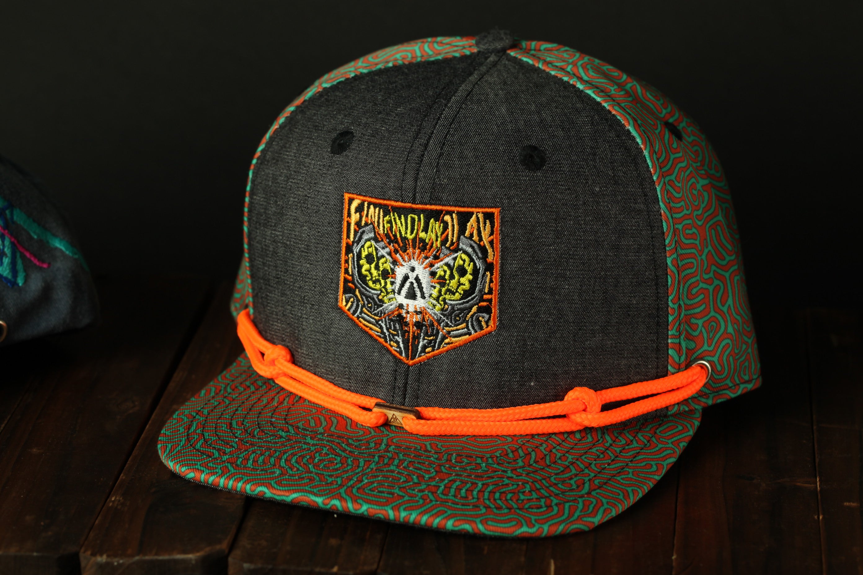 A black baseball cap with a colorful, patterned design on the front, featuring a patch with an abstract, skull-like design and the text "FAMINE D'ANIMA" printed on it.