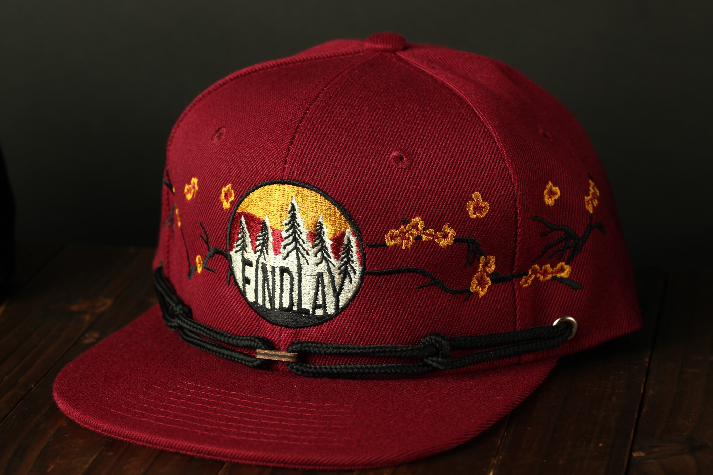 A red baseball cap with a floral design and the word "FINDlay" printed on it.