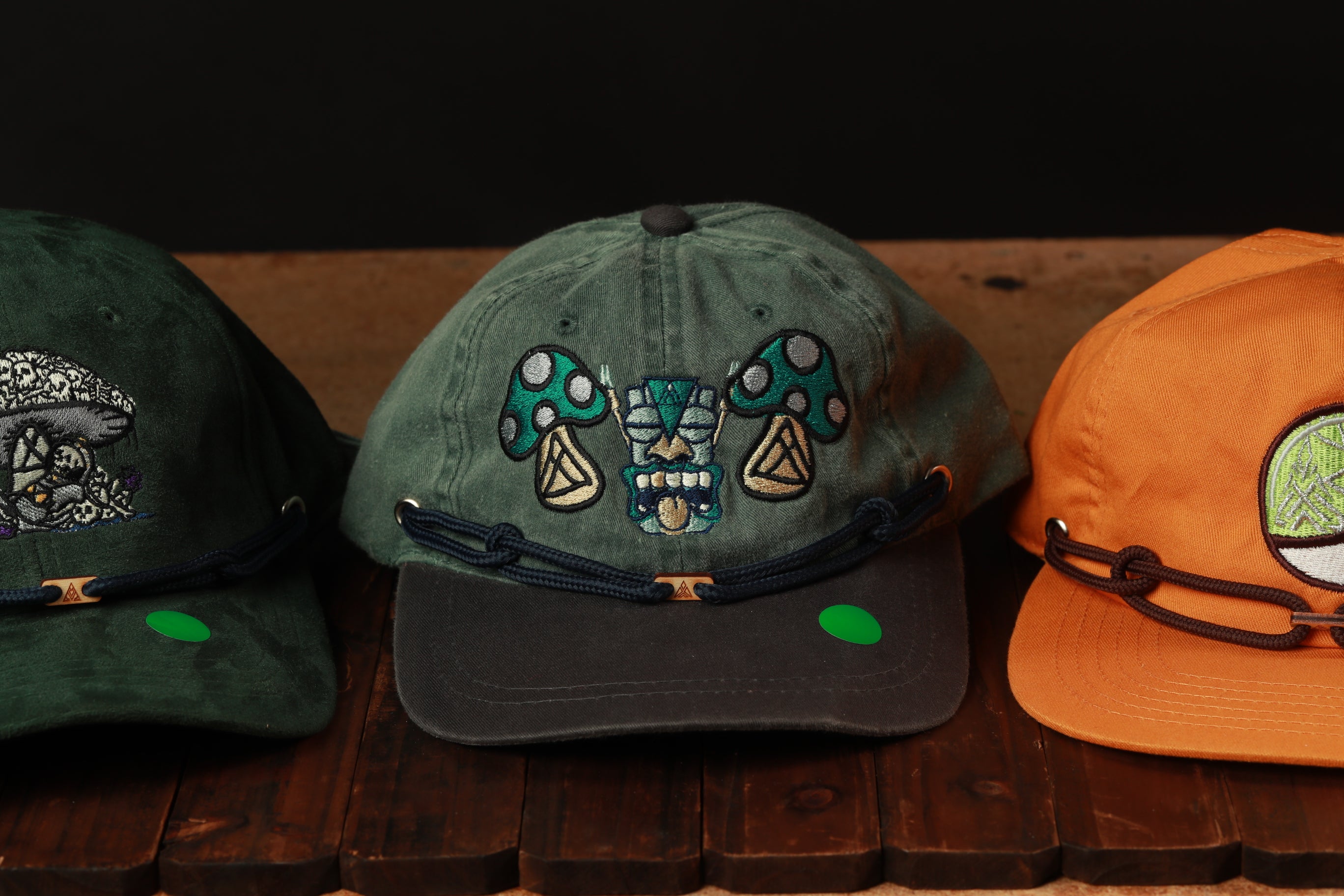 Three baseball caps with different designs and colors are displayed on a wooden surface.