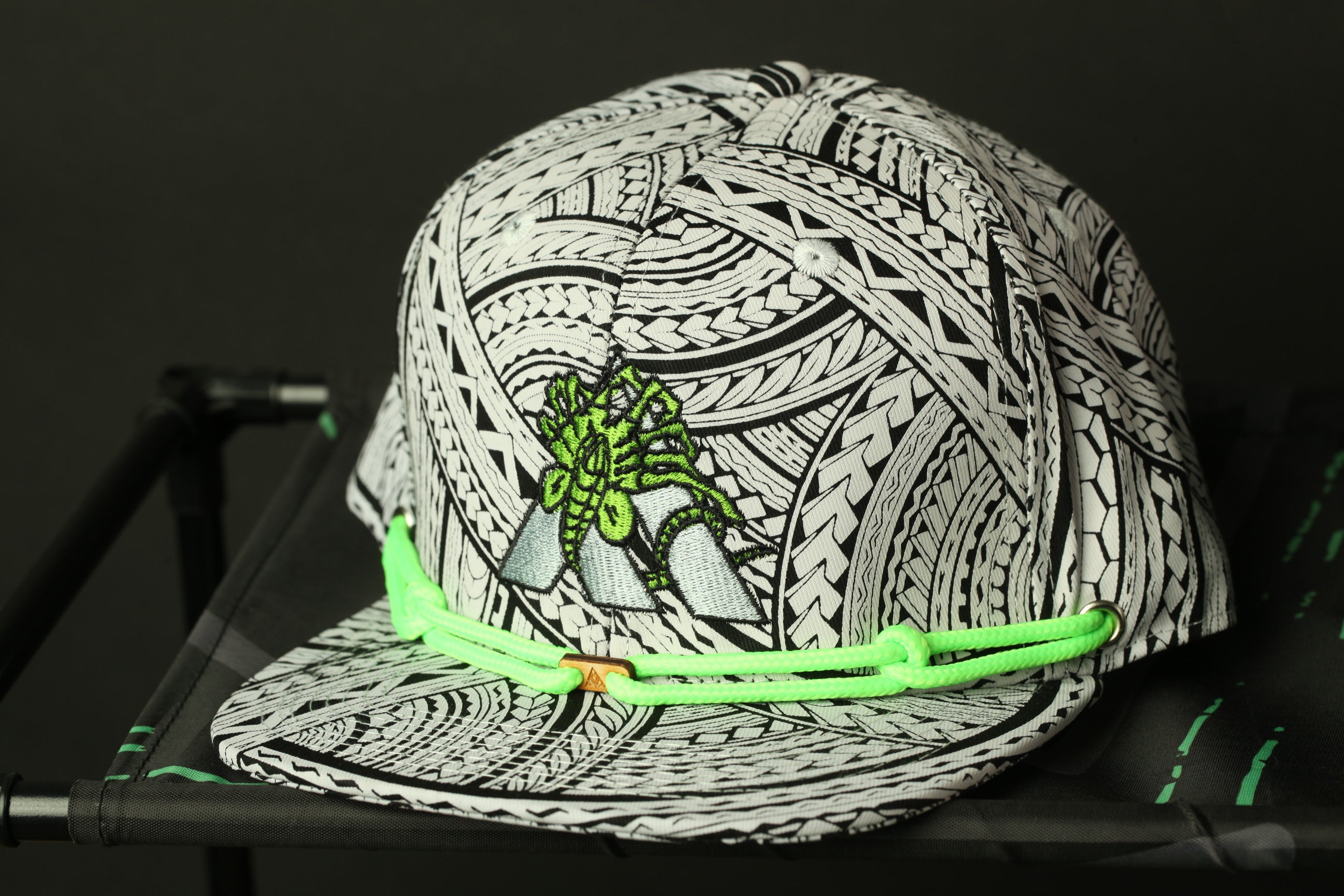 A close-up image of a black and white patterned baseball cap with a green string.