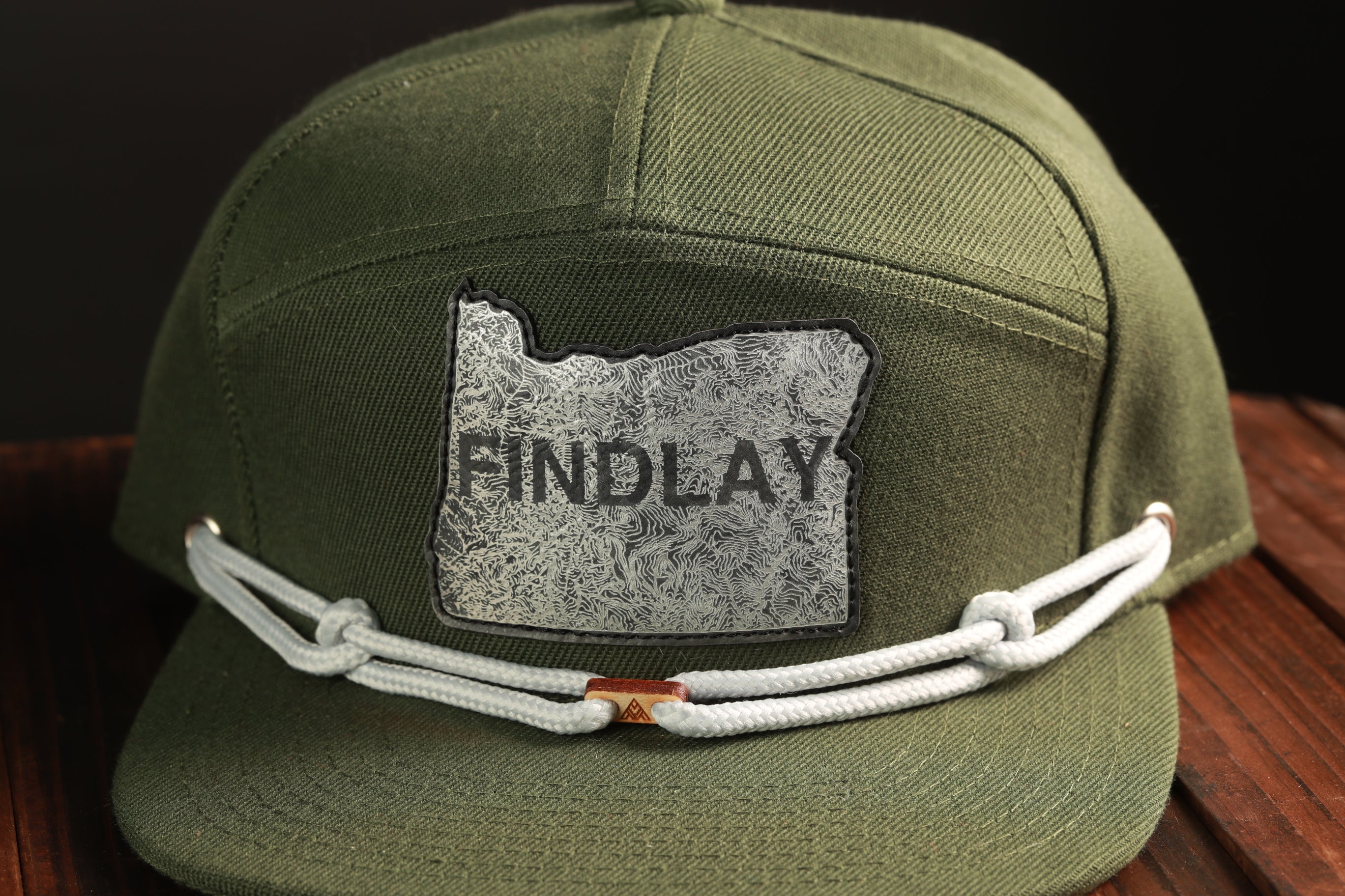 A green baseball cap with a patch on the front displaying the word "FIND LAY".