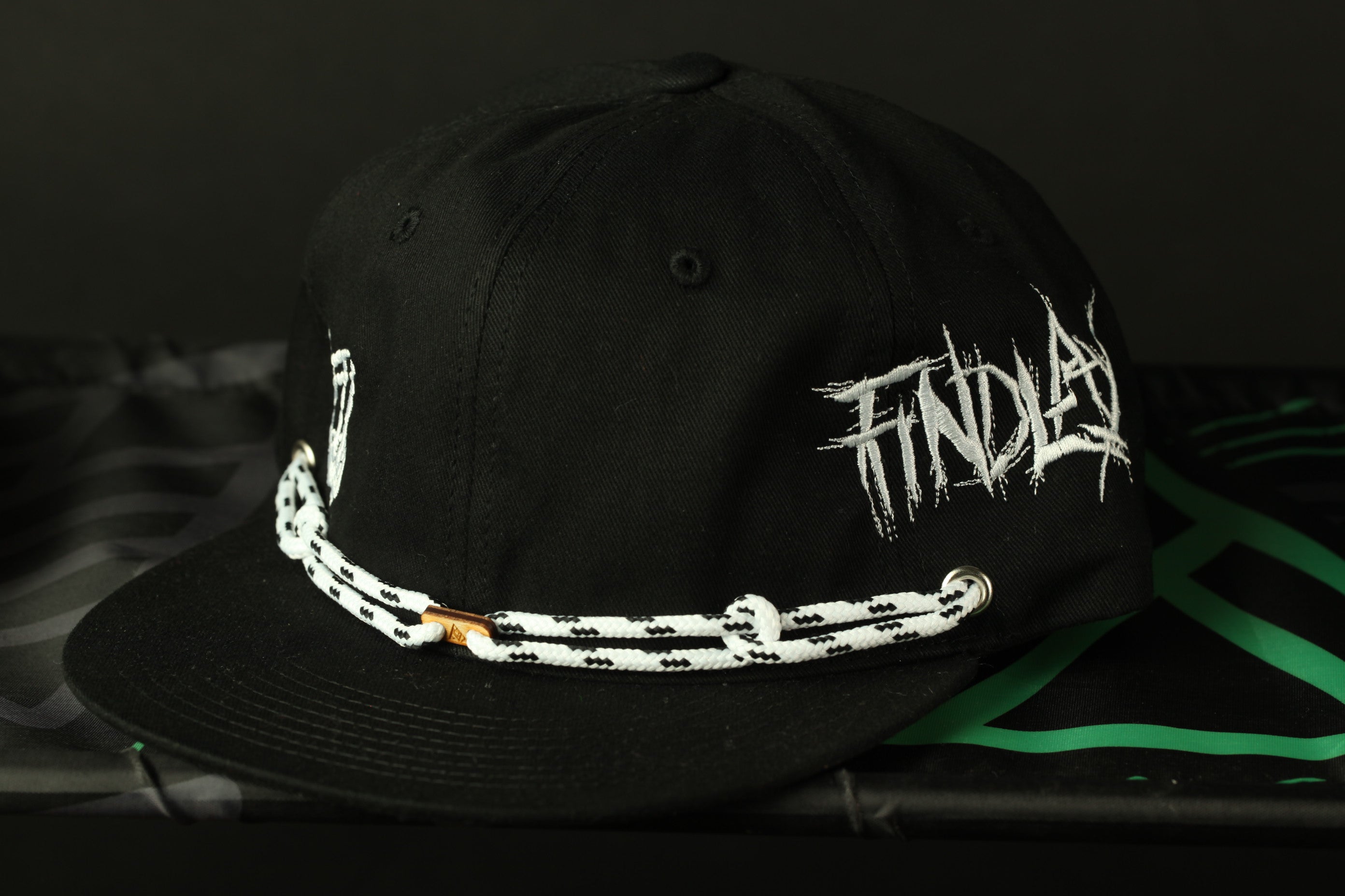 A black baseball cap with white text and a chain strap.