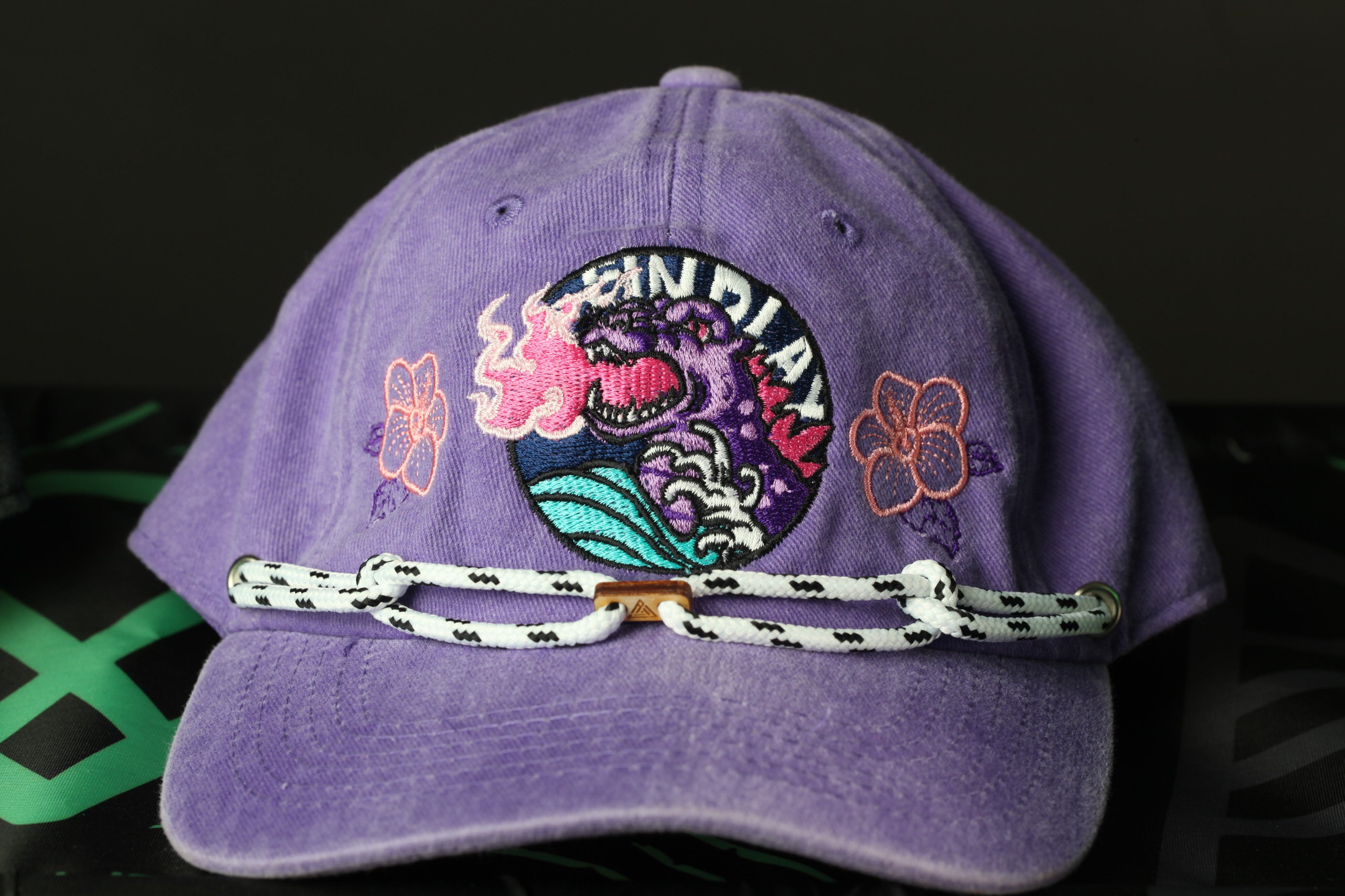 A purple baseball cap with a colorful graphic design and floral motifs.