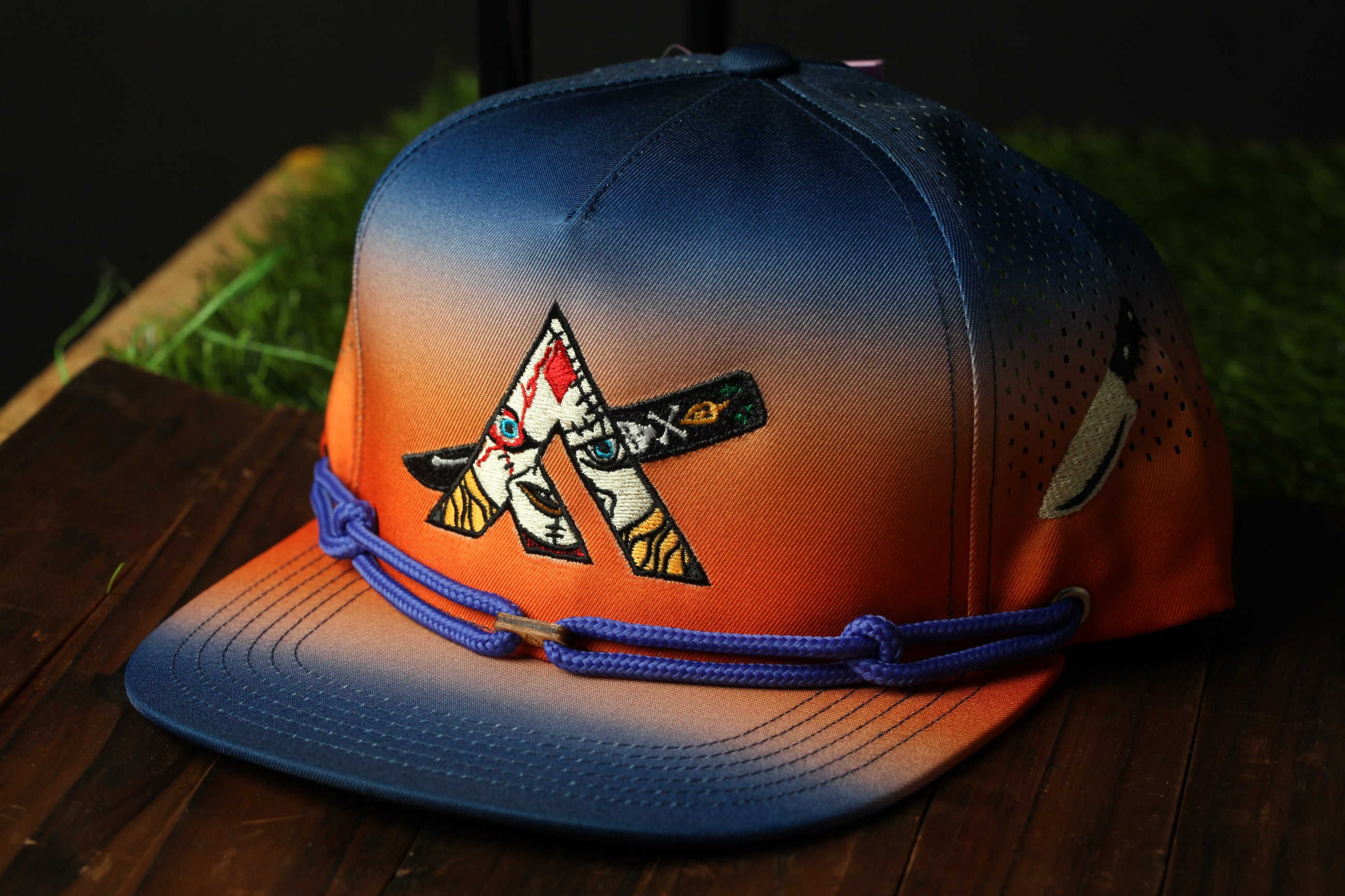 A colorful baseball cap with a gradient design and a logo on the front, sitting on a wooden surface.