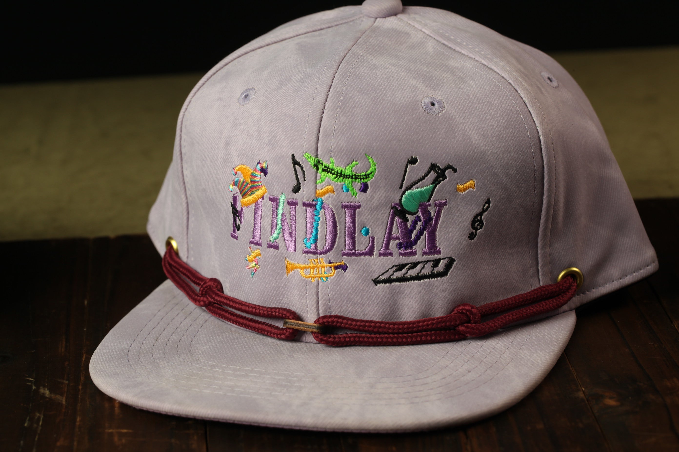 A gray baseball cap with a maroon bandana and colorful embroidered text on the front.
