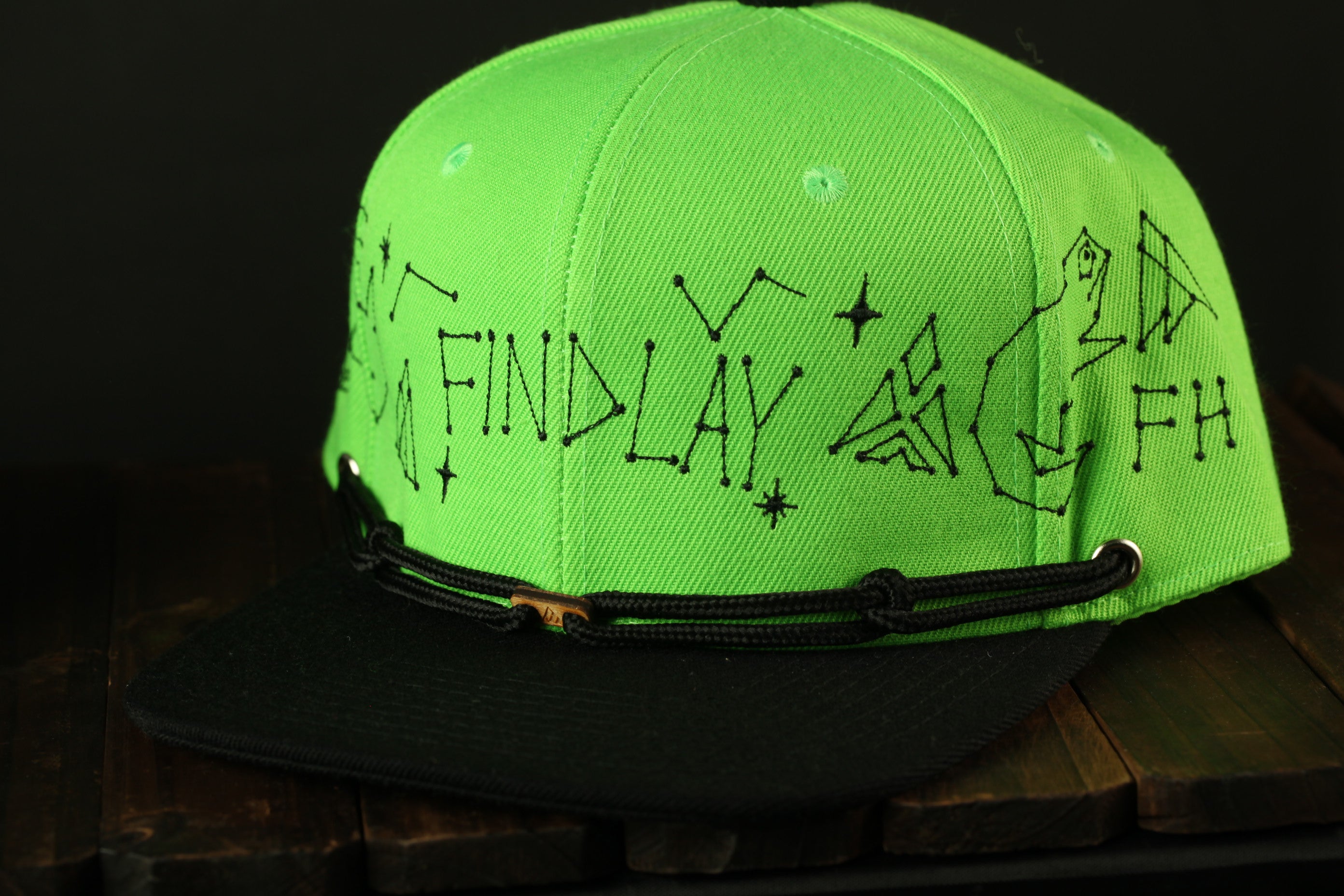 A neon green baseball cap with black text and designs on it.