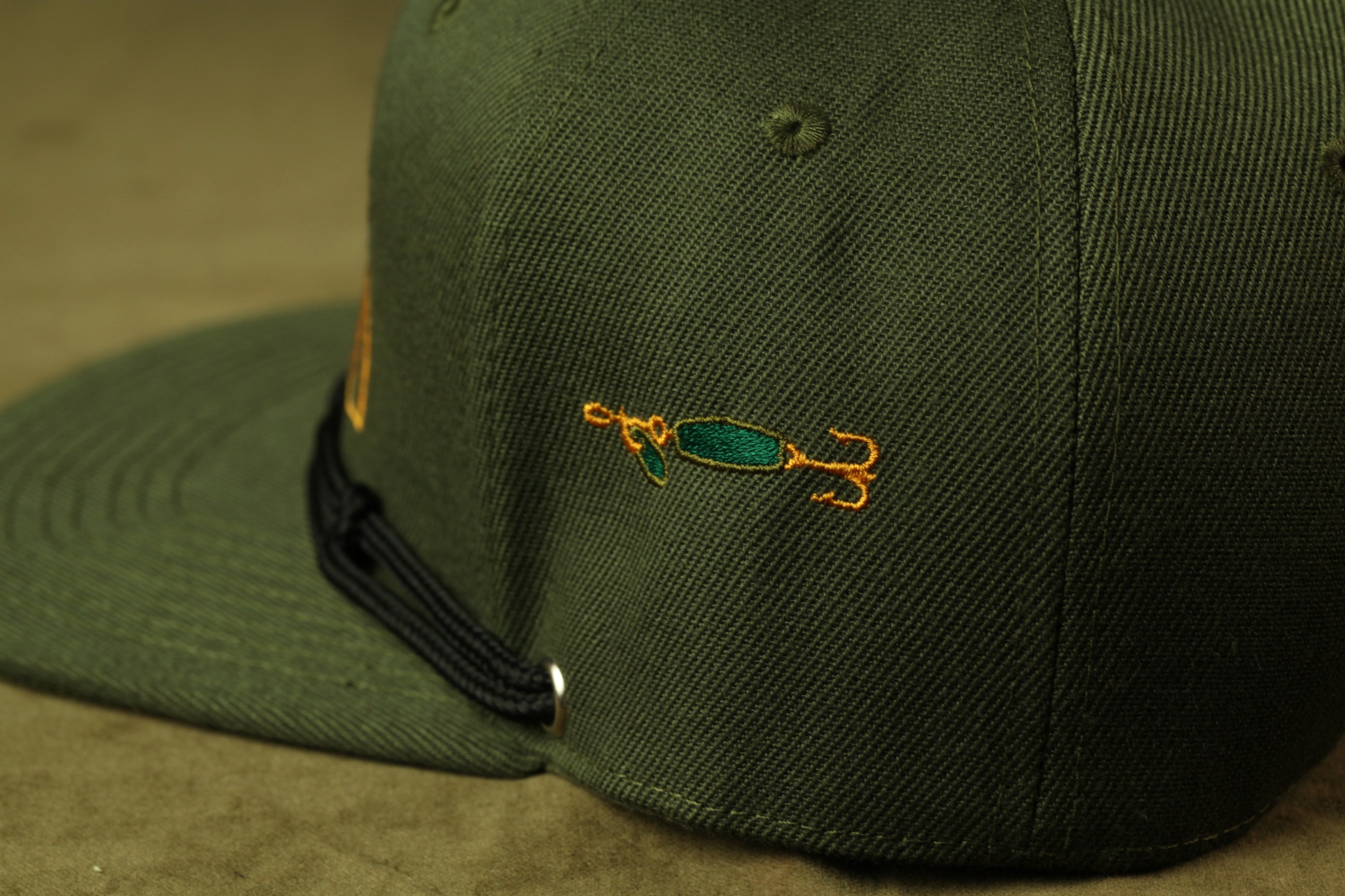 A close-up view of a green baseball cap with a fishing-themed embroidered patch on the front.