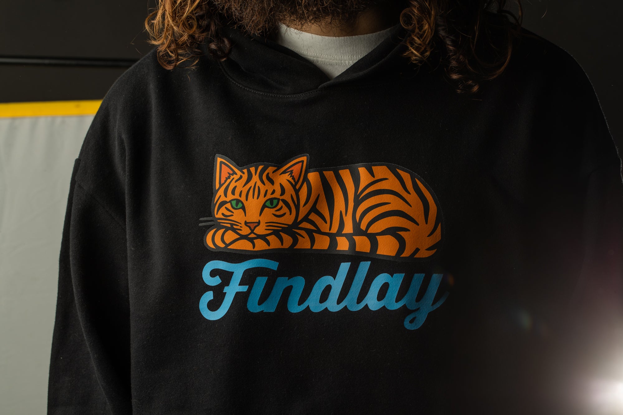 A person wearing a black hoodie with a graphic of a tiger and the word "Findlay" printed on it.