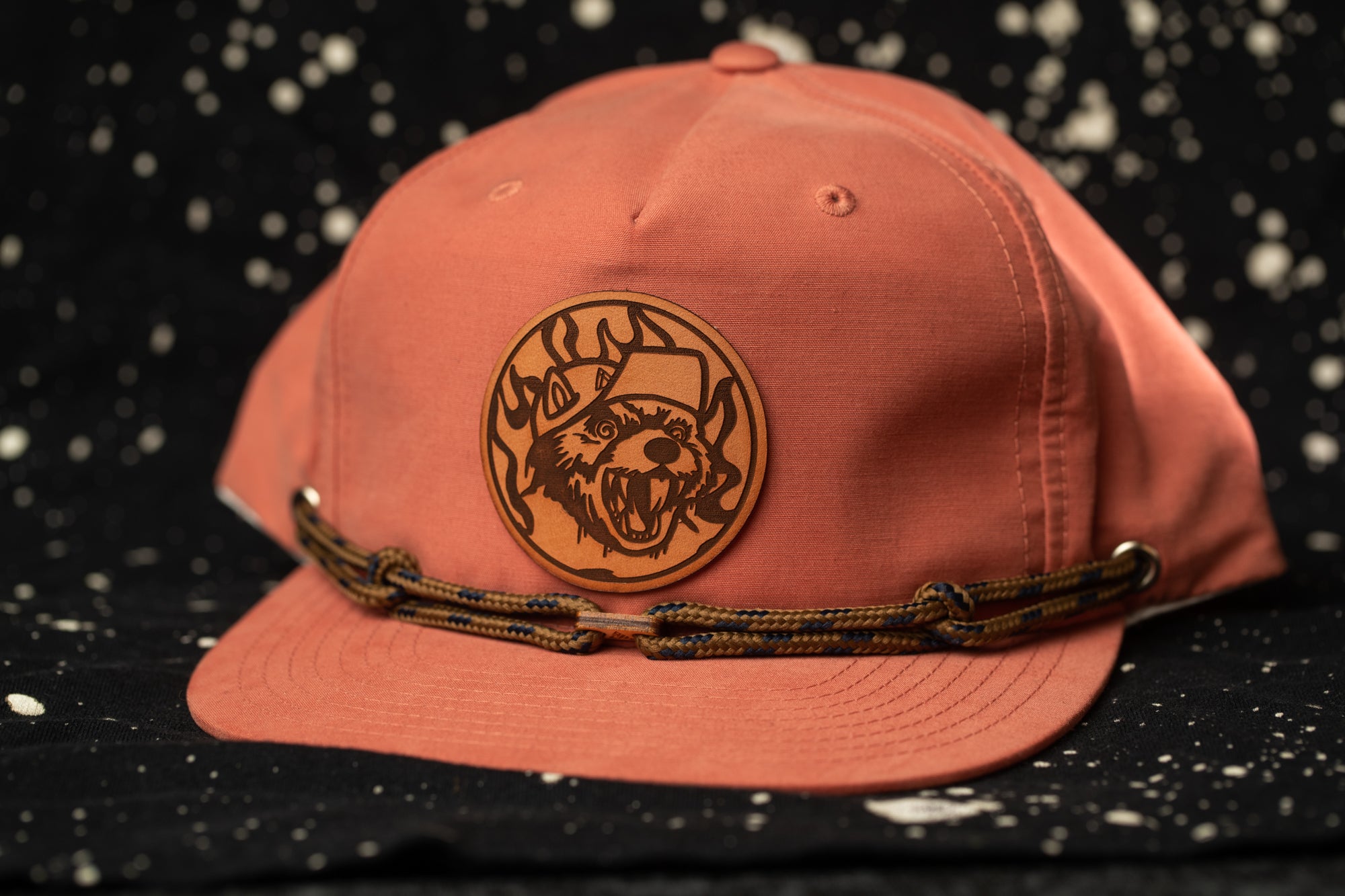 A pink baseball cap with a brown circular logo featuring a fierce-looking dog.