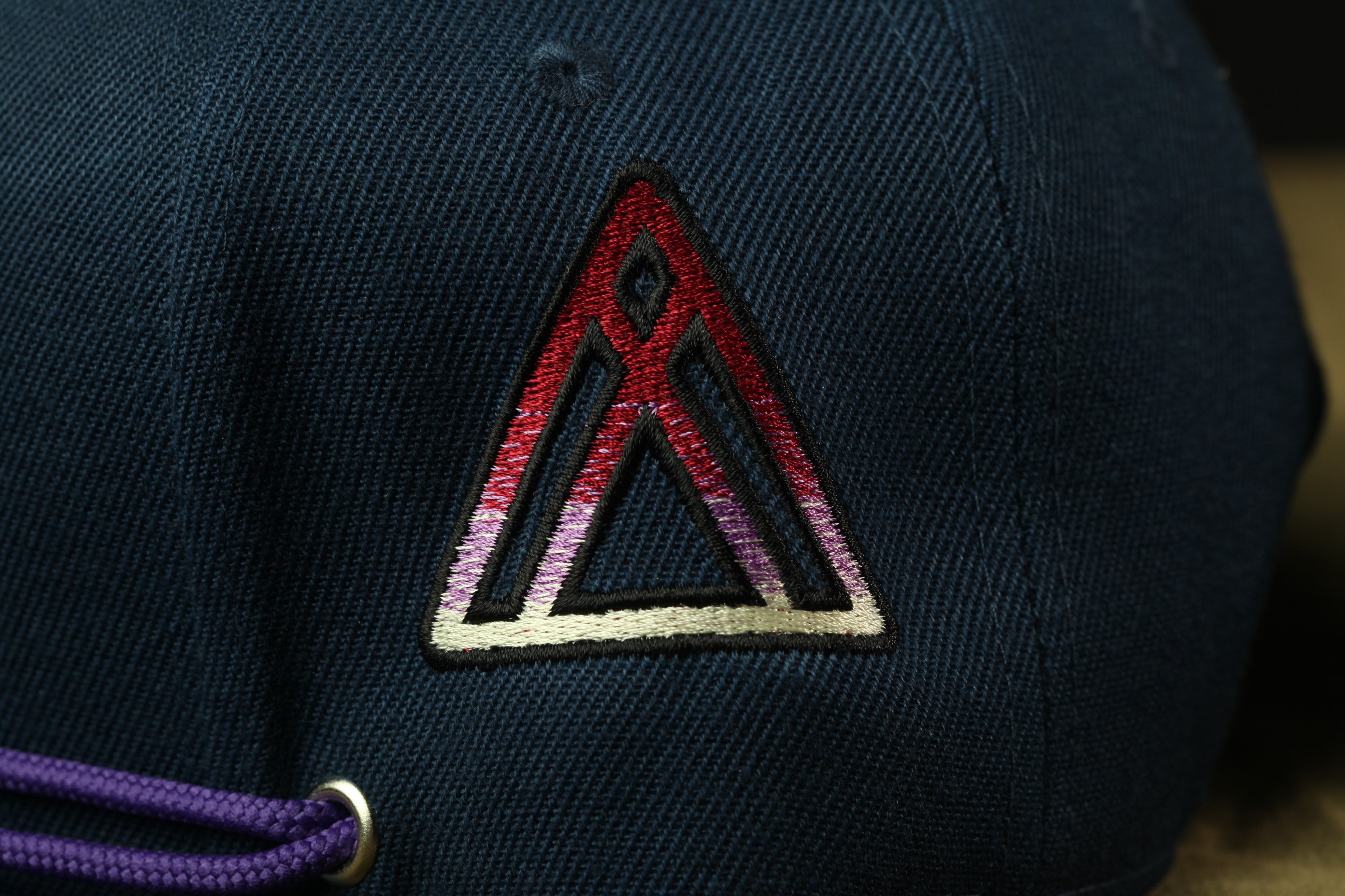 A close-up view of a dark blue fabric with a red and white geometric pattern, resembling a triangle or a logo.