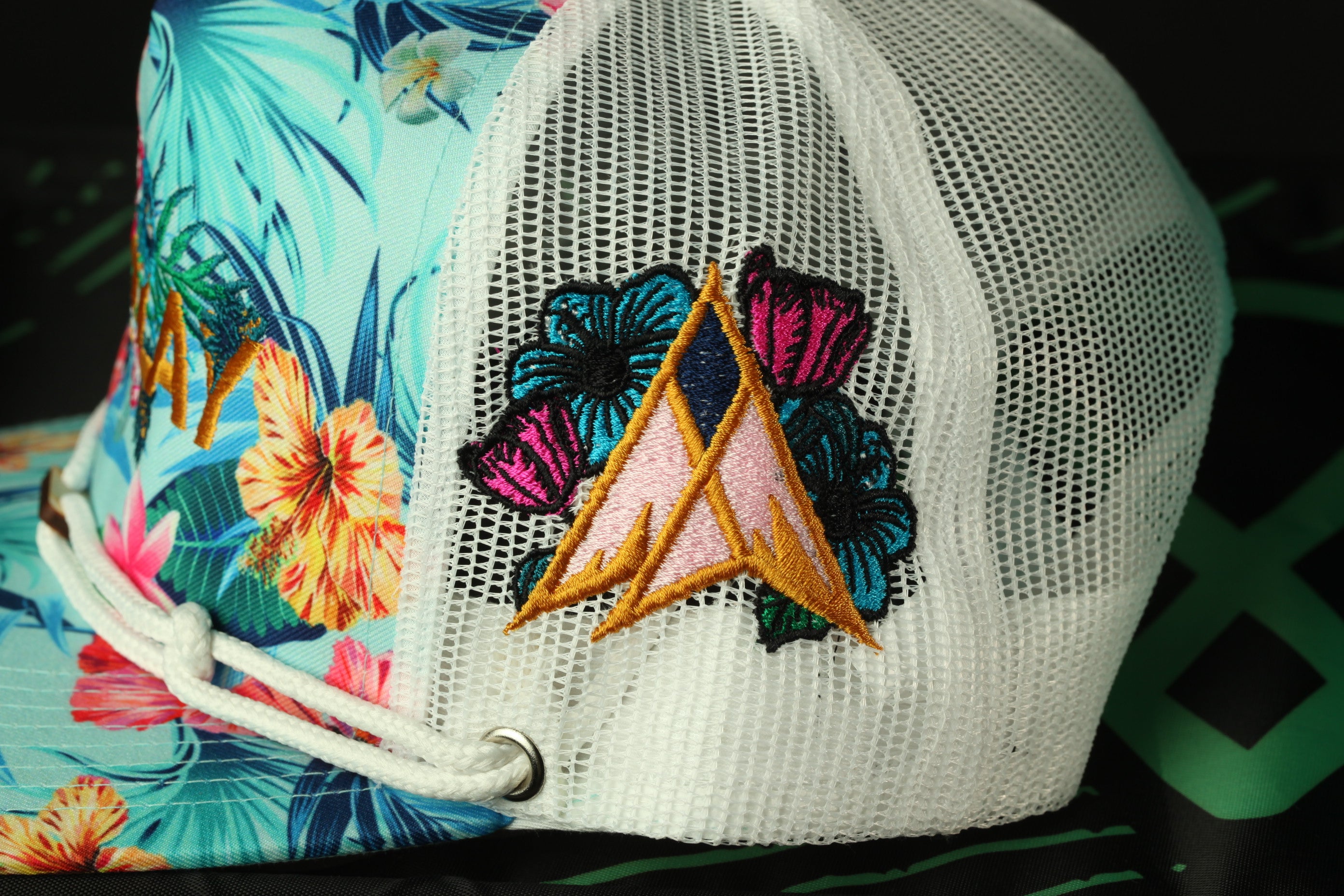 A colorful floral pattern on a white mesh fabric, with a pink and blue flower design on the side of the fabric.