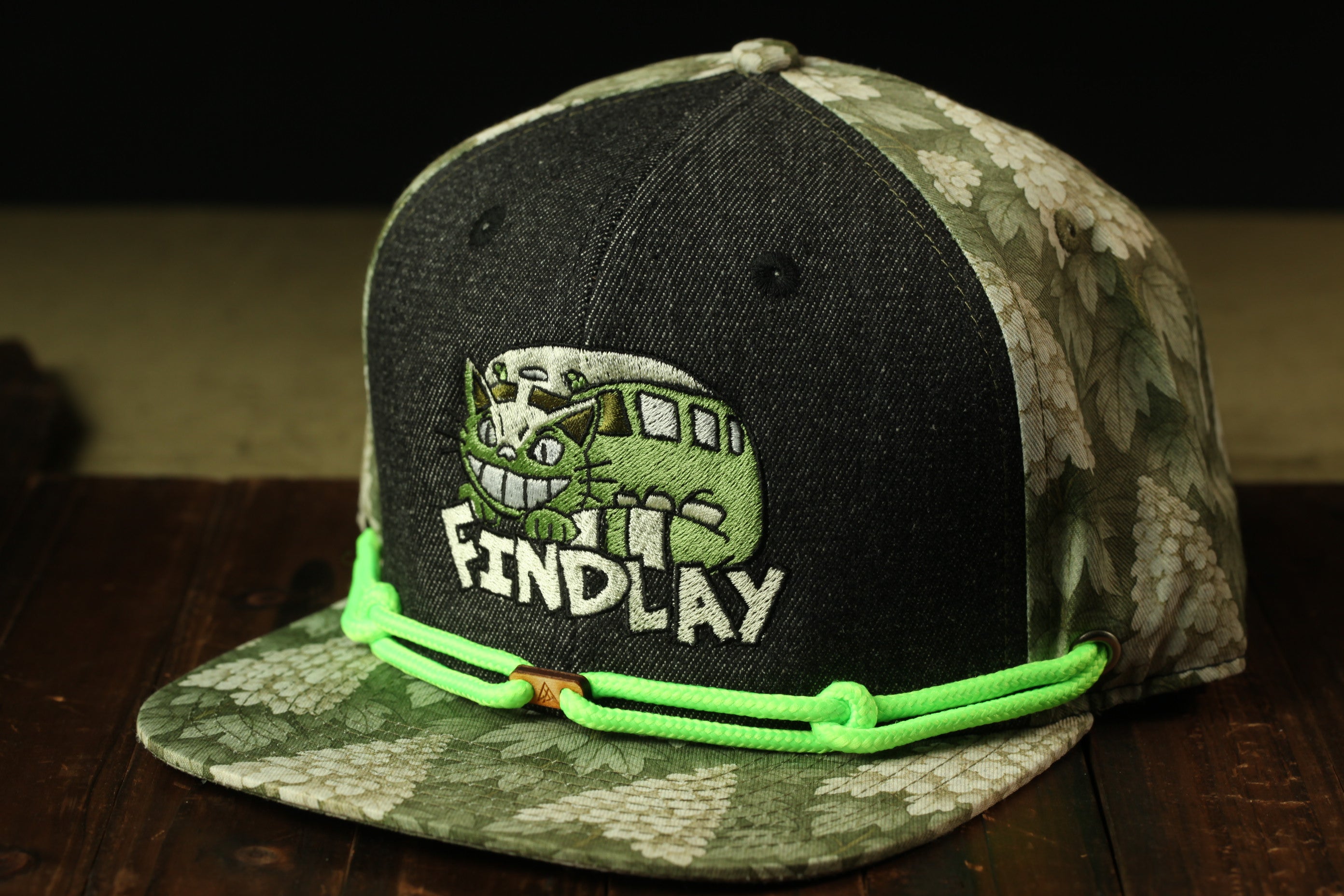 A black and green baseball cap with a cartoon character and the text "FIND LAY" printed on it.