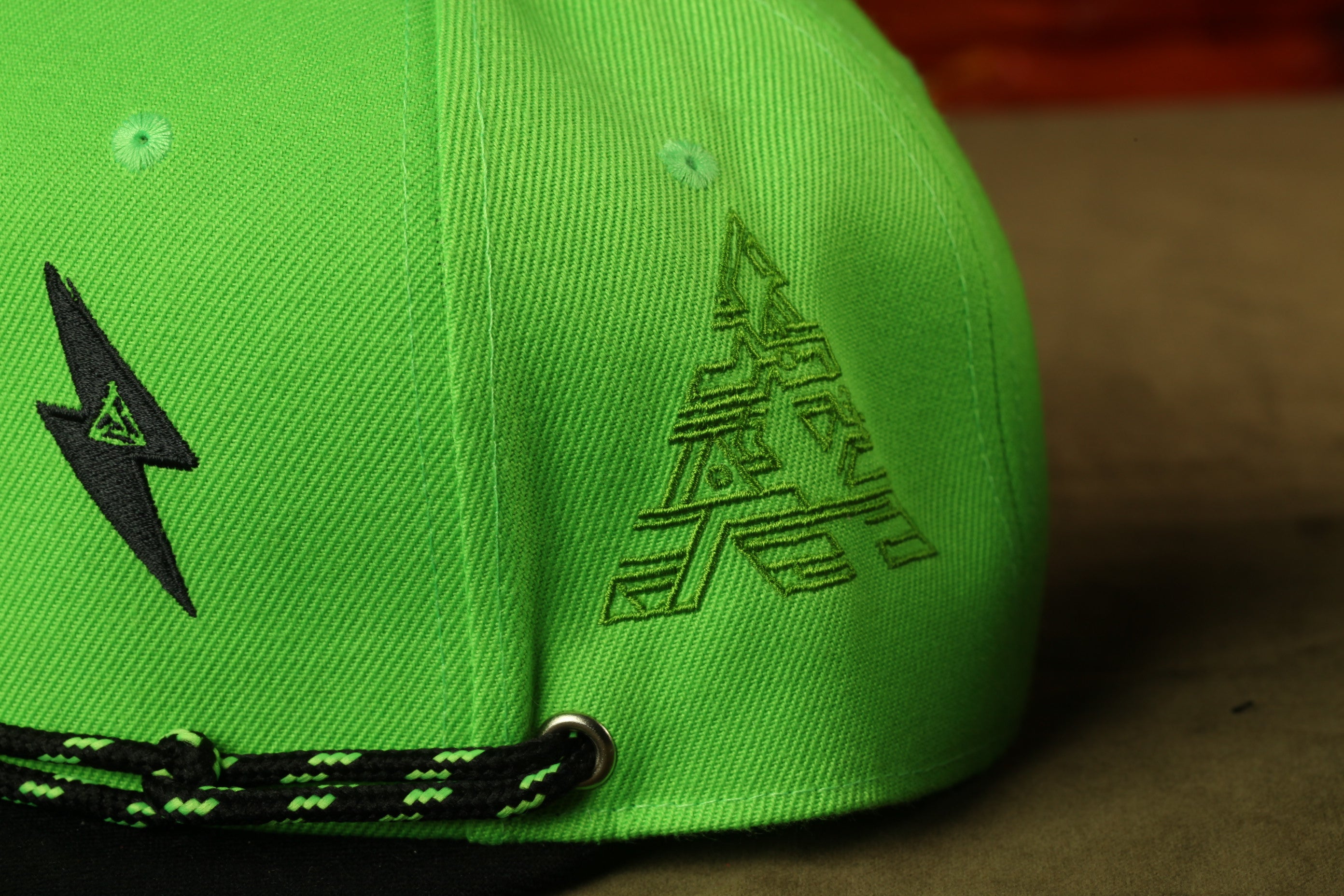 A close-up view of a bright green baseball cap with a black lightning bolt design on the left side.
