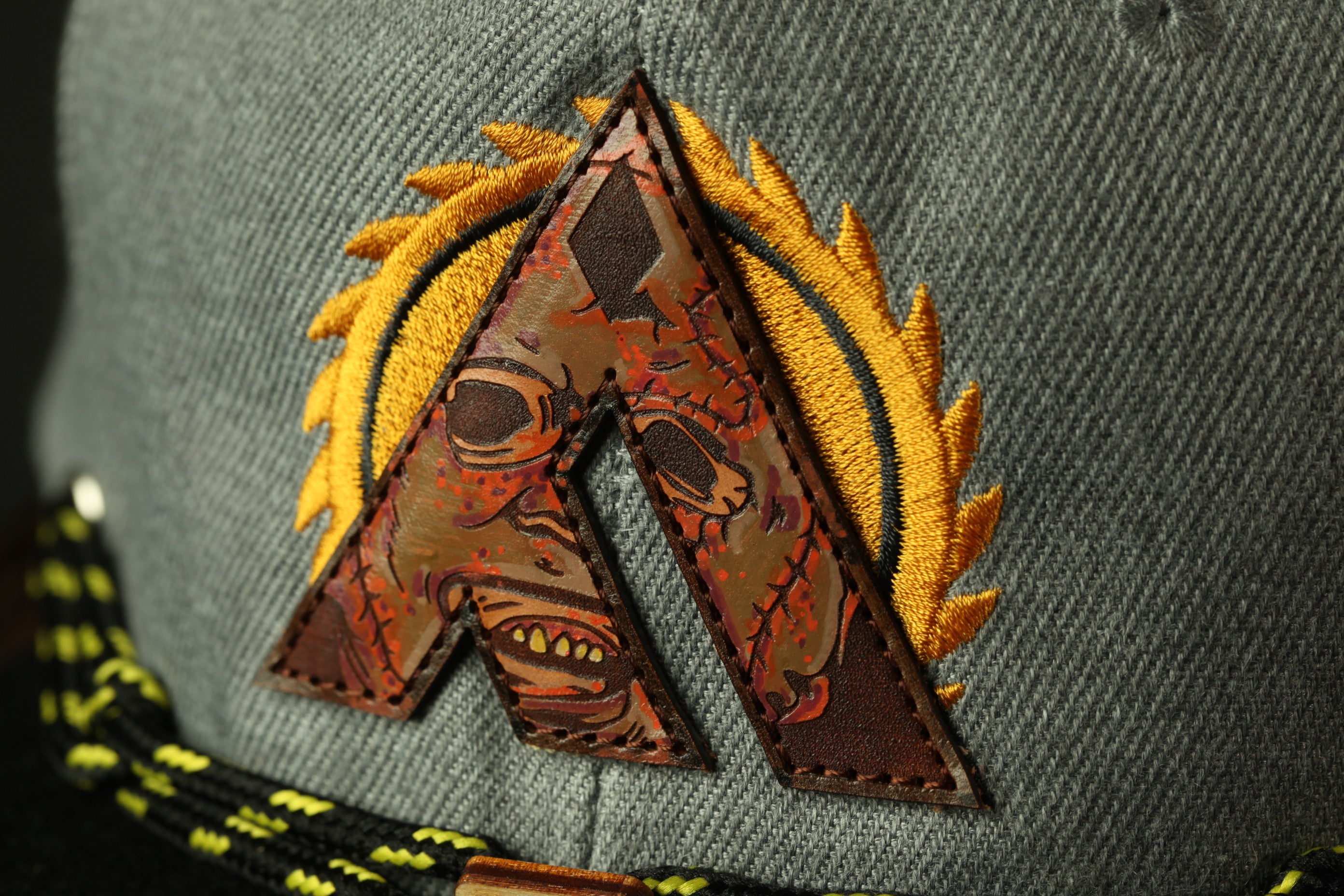 A close-up view of a gray fabric with a large, stylized letter "A" on it, featuring a face and a saw blade design.
