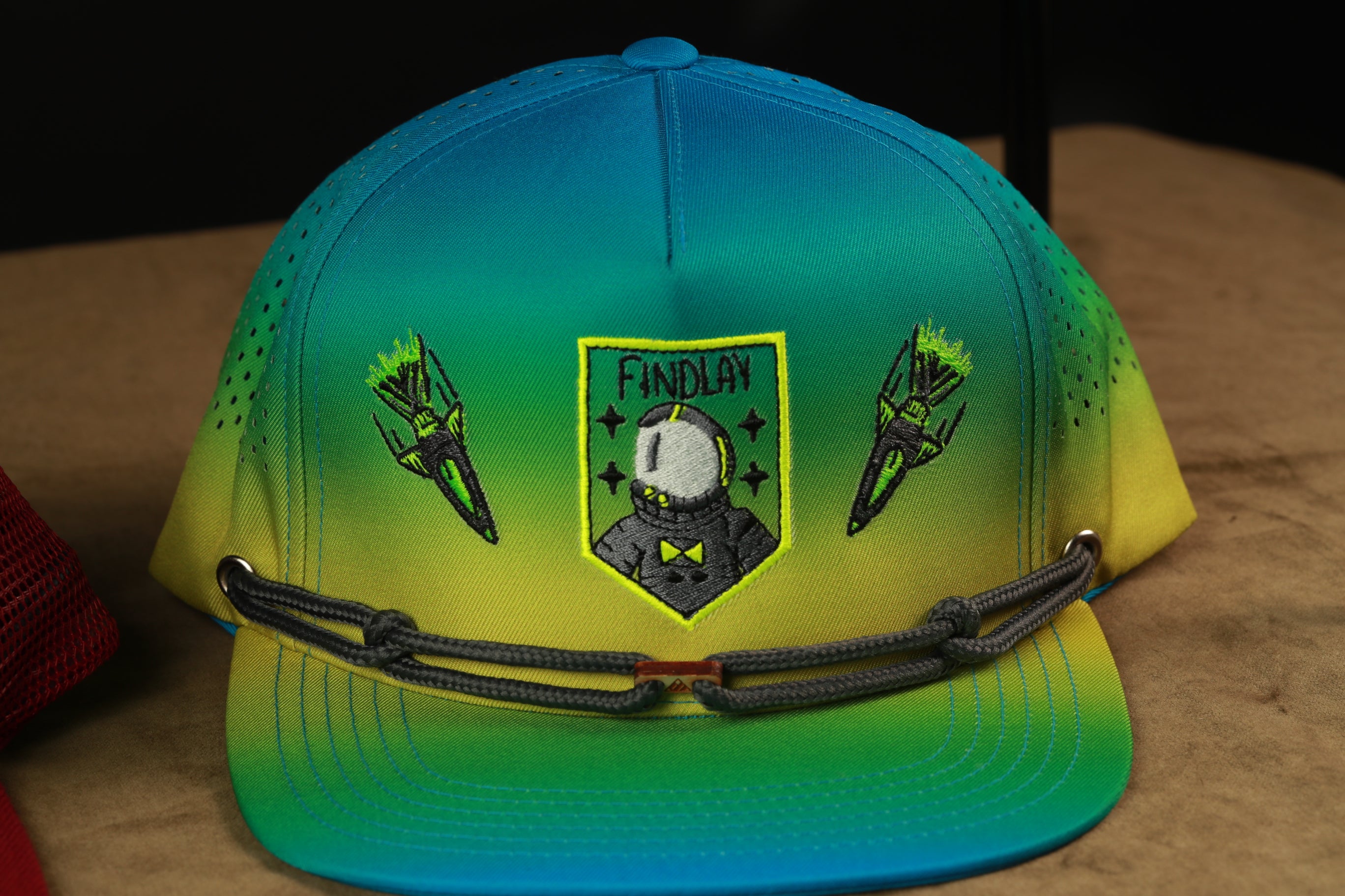 A colorful baseball cap with a military-style helmet design and a shield-shaped patch featuring a character.