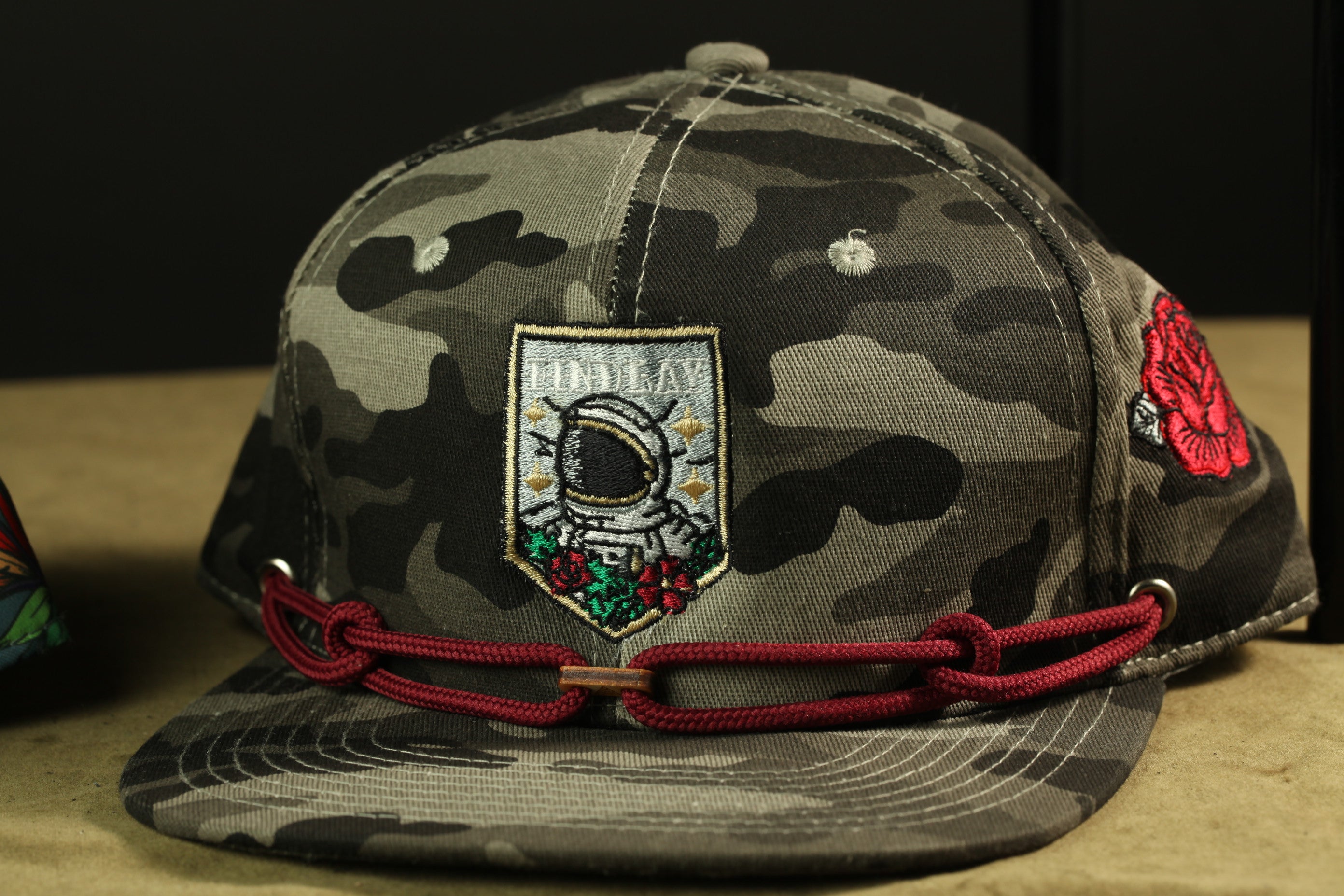 A camouflage baseball cap with a patch featuring an astronaut and the word "FINALLY" on it.