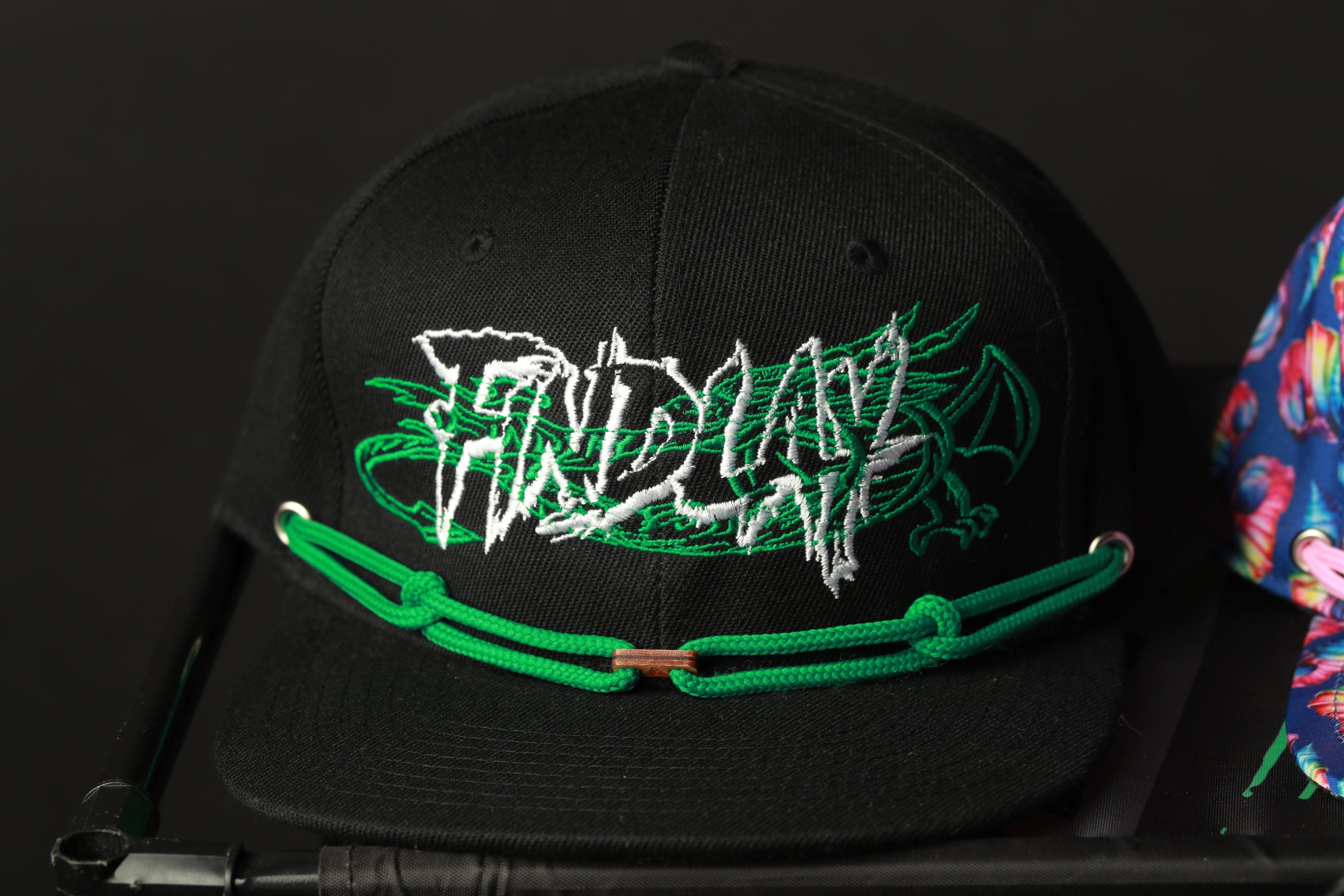 A black baseball cap with a green rope strap and the word "FRIDAY" embroidered on it.