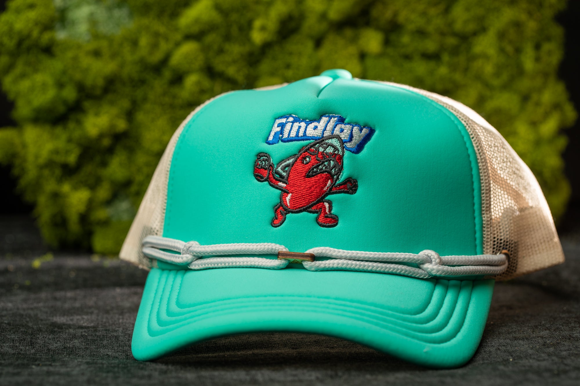 A turquoise baseball cap with a cartoon character on it, featuring the word "Findlay" on the front.