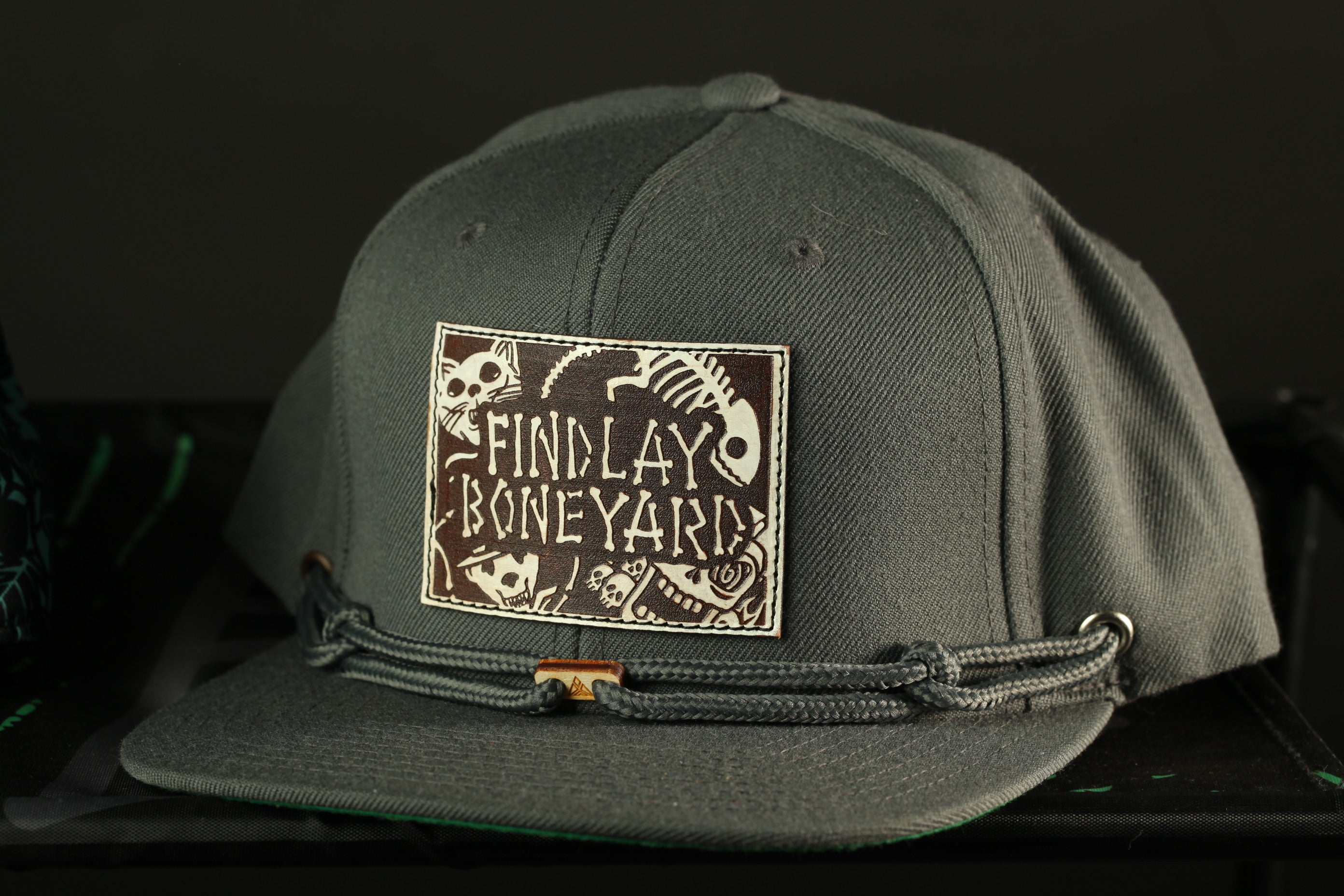 A gray baseball cap with a patch on the front that says "FIND LAY BONEYARD".