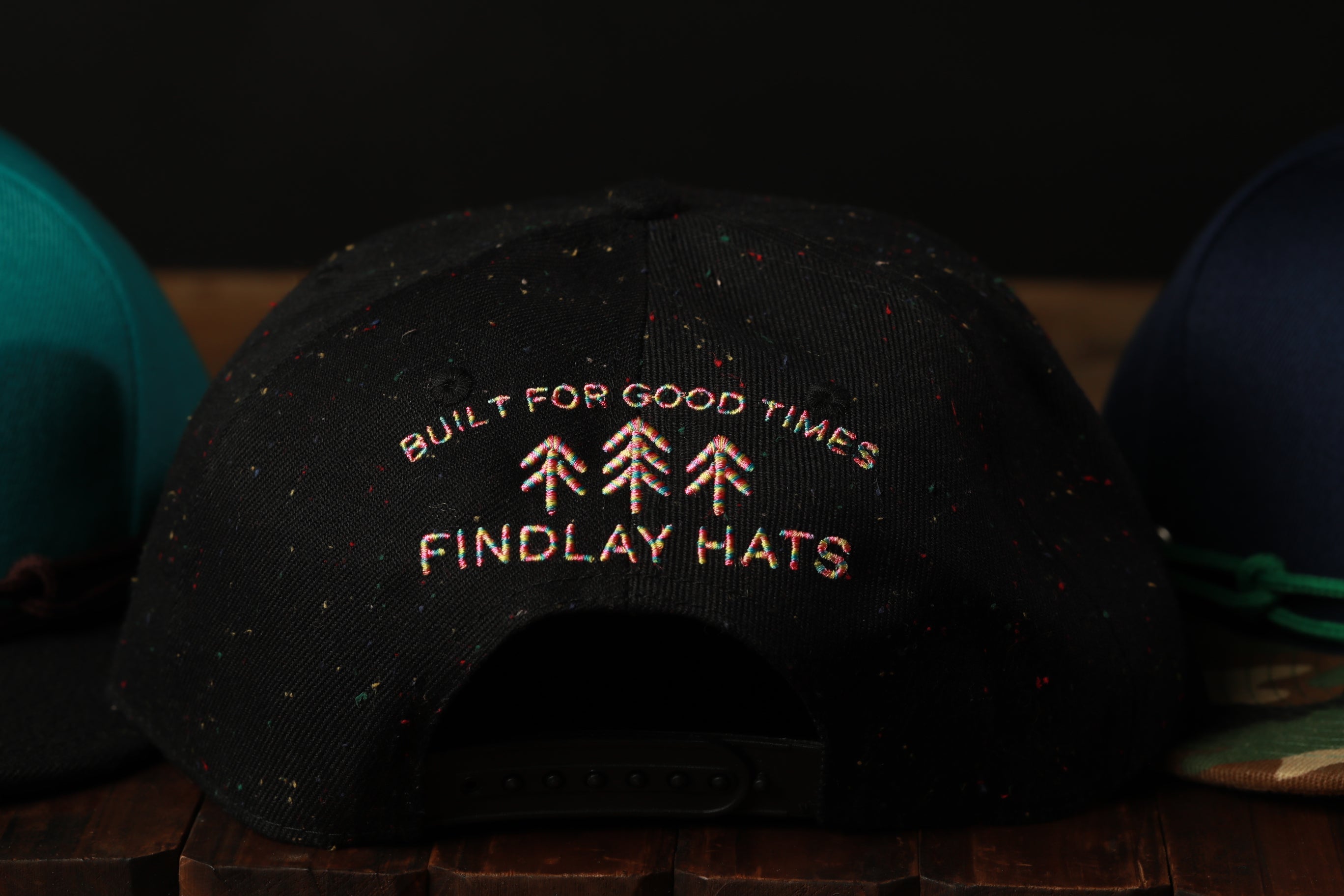 a close-up view of a black baseball cap with text and graphics on it, placed on a wooden surface.