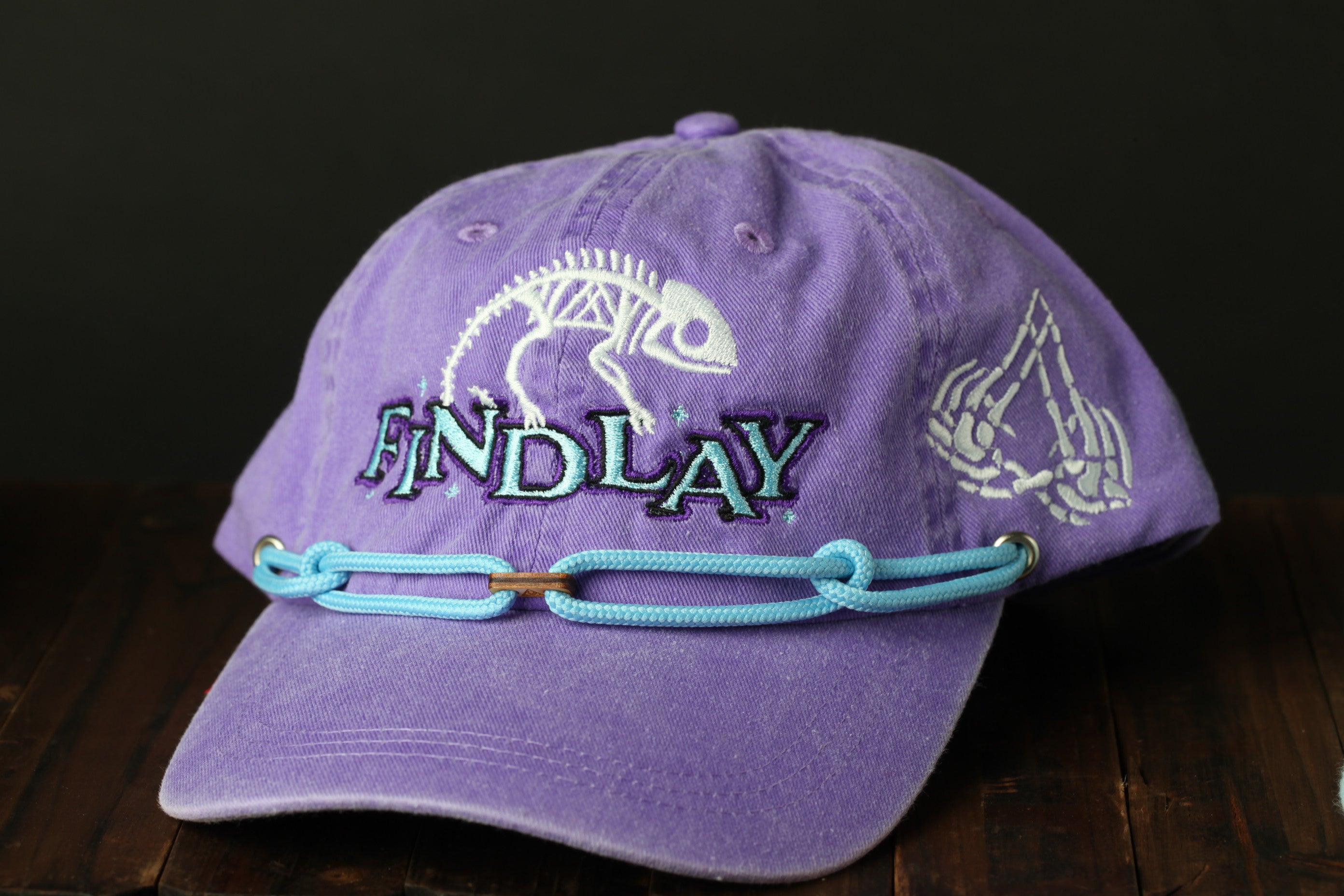 A purple baseball cap with a skeleton design and the word "ENDLAY" printed on it.