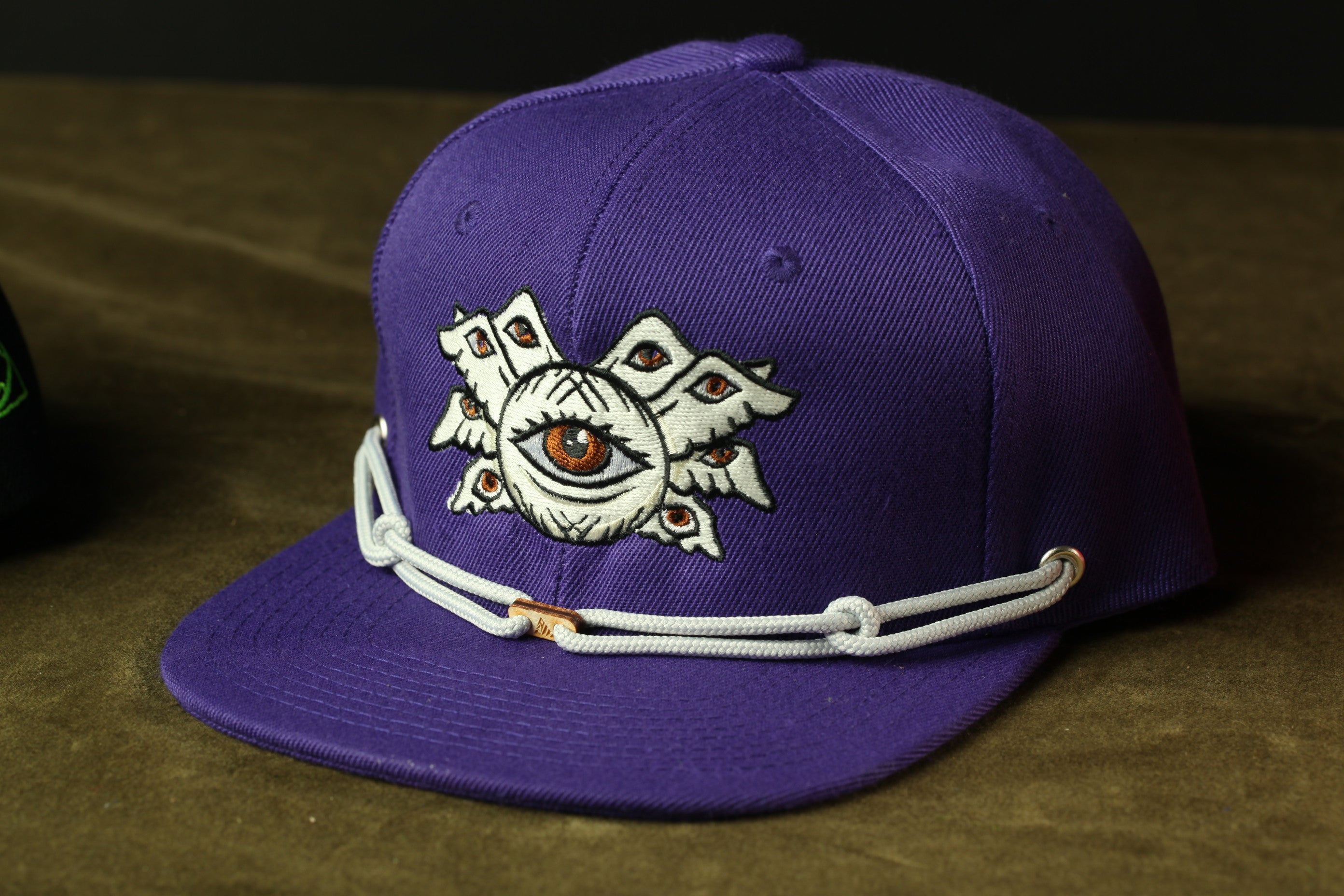A purple baseball cap with an eye design on the front.