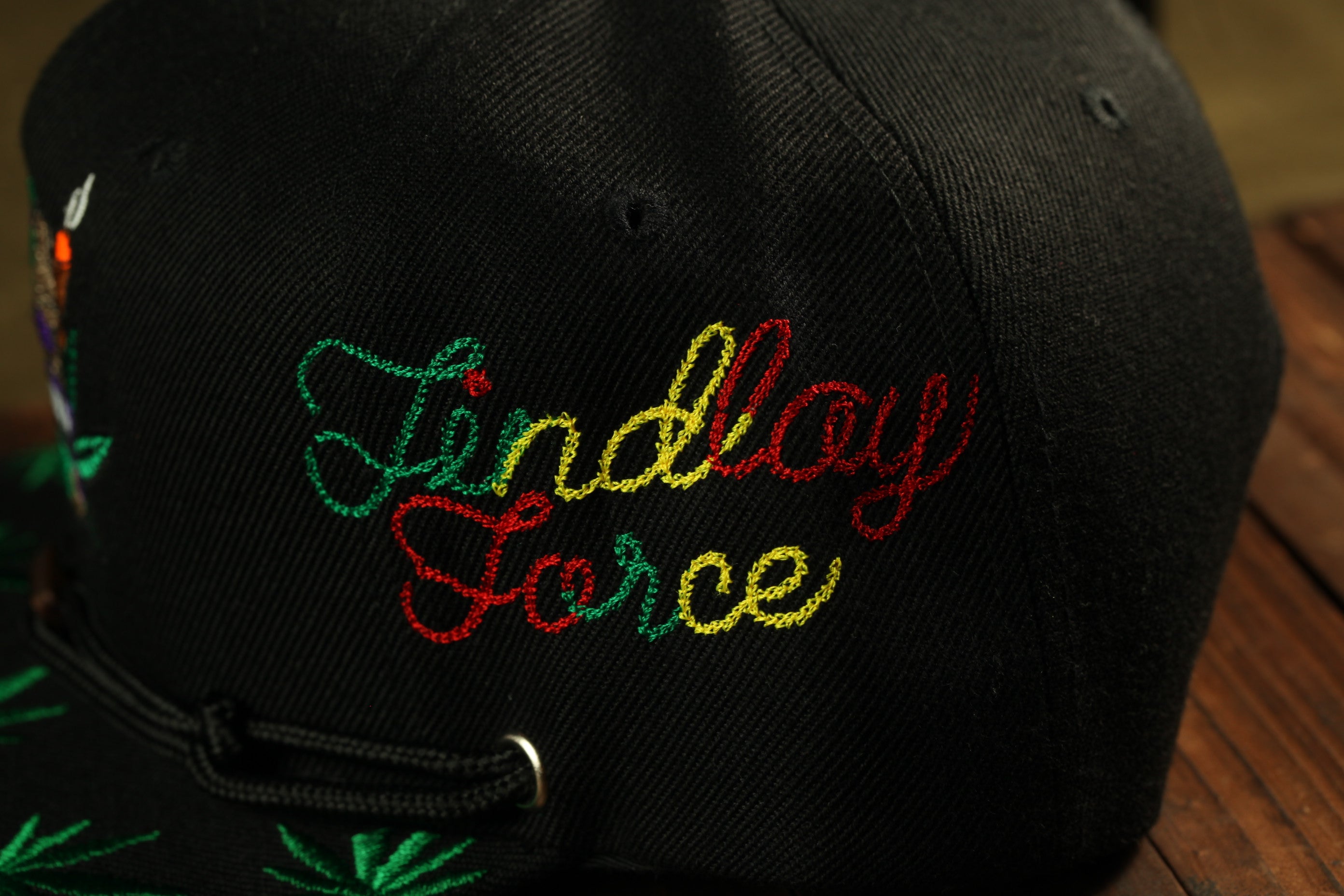 A close-up view of a black baseball cap with colorful embroidered text on the front.