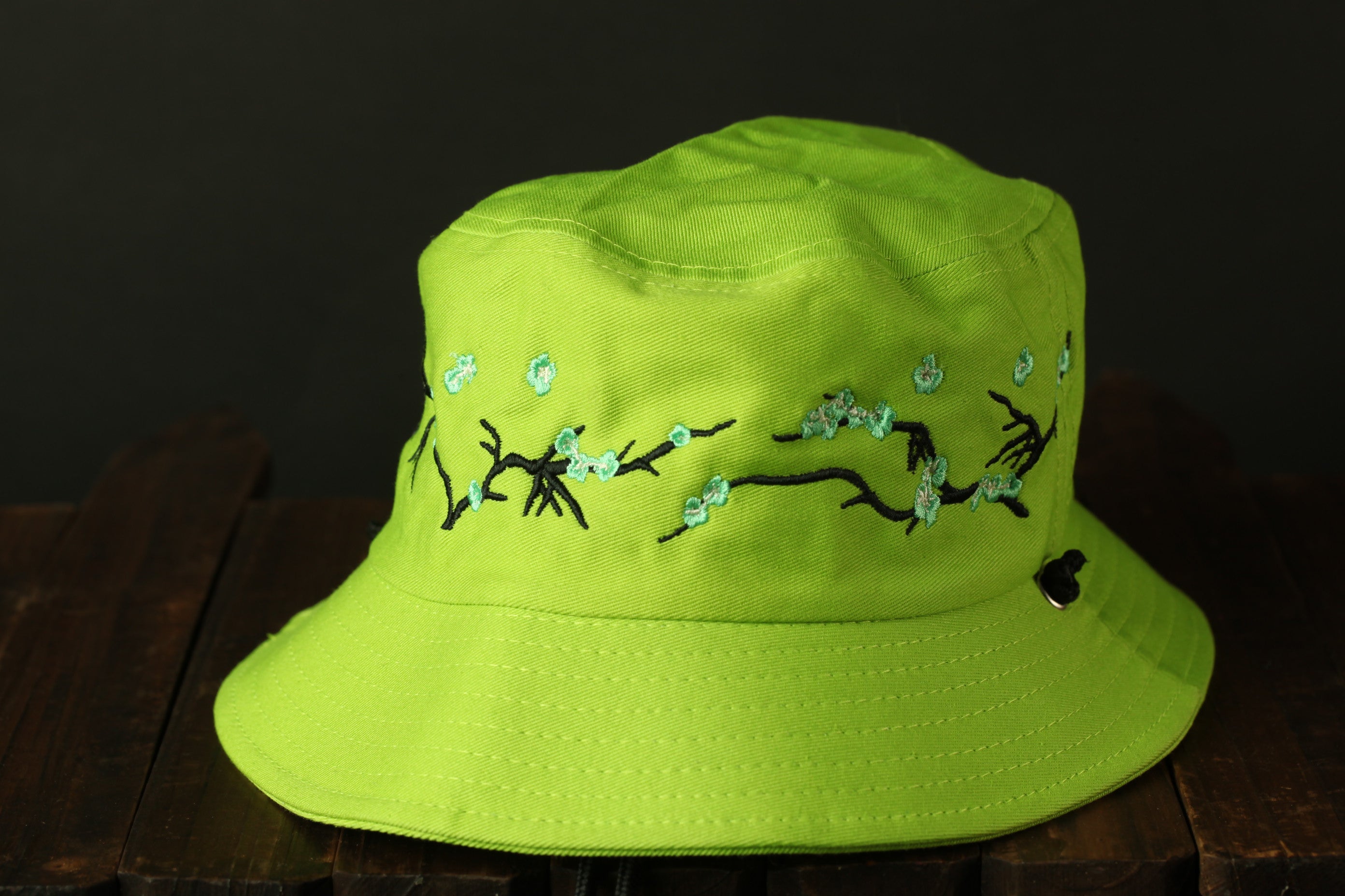 A bright green bucket hat with a floral embroidered design on the front.