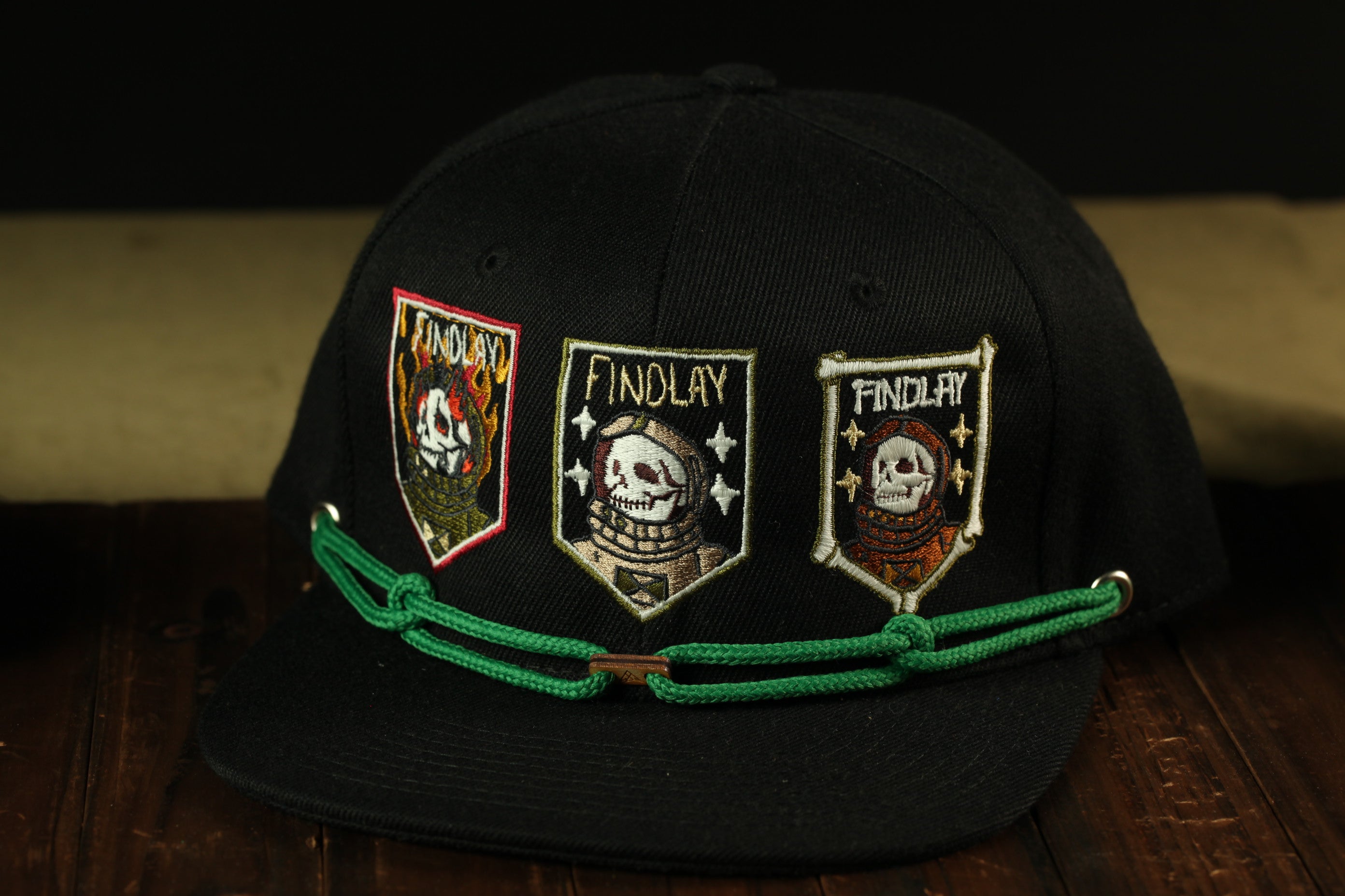 A black baseball cap with three patches on it, each featuring a skull and the word "FINDLAY" written on them.