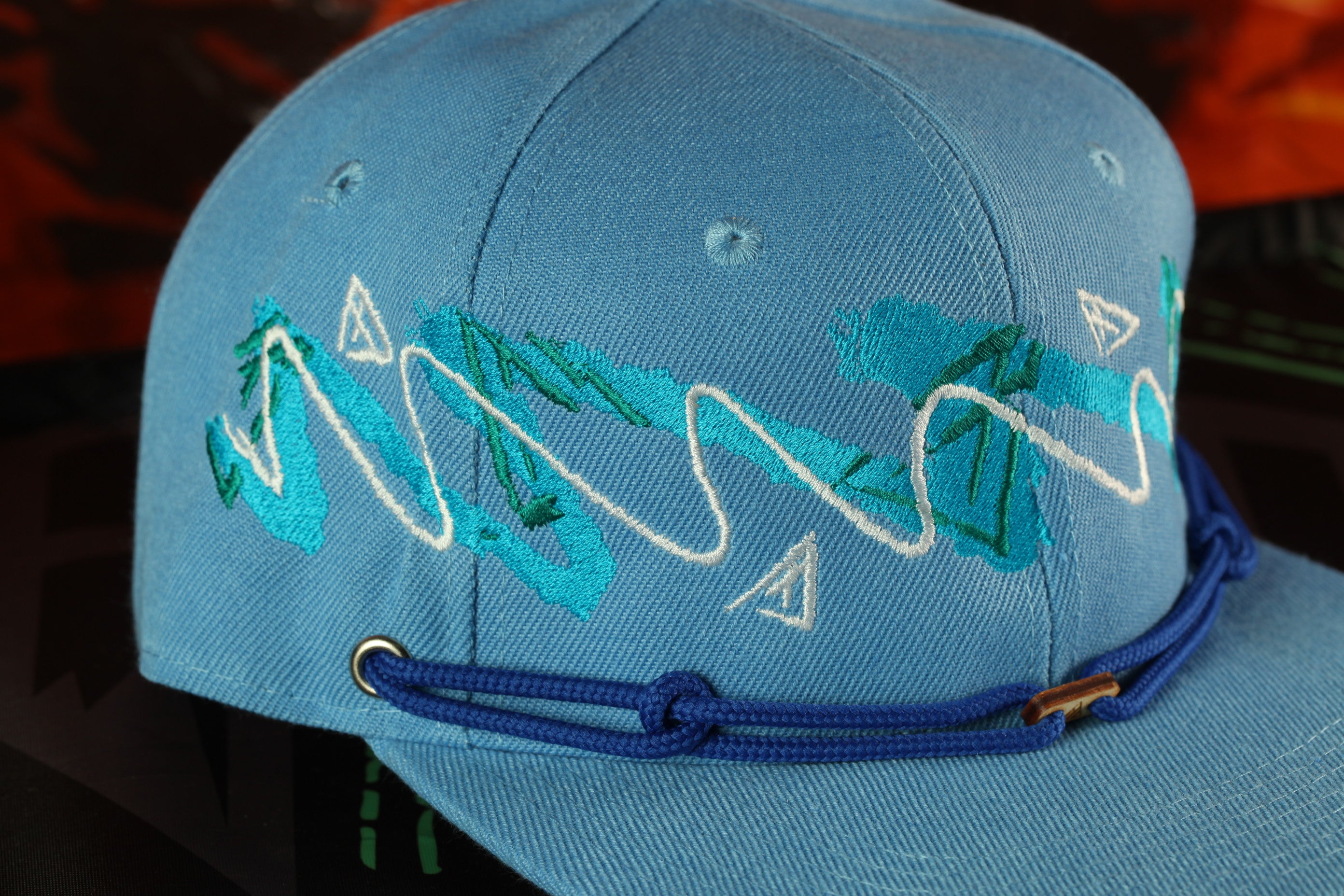 A close-up view of a blue baseball cap with a unique embroidered design on the front.